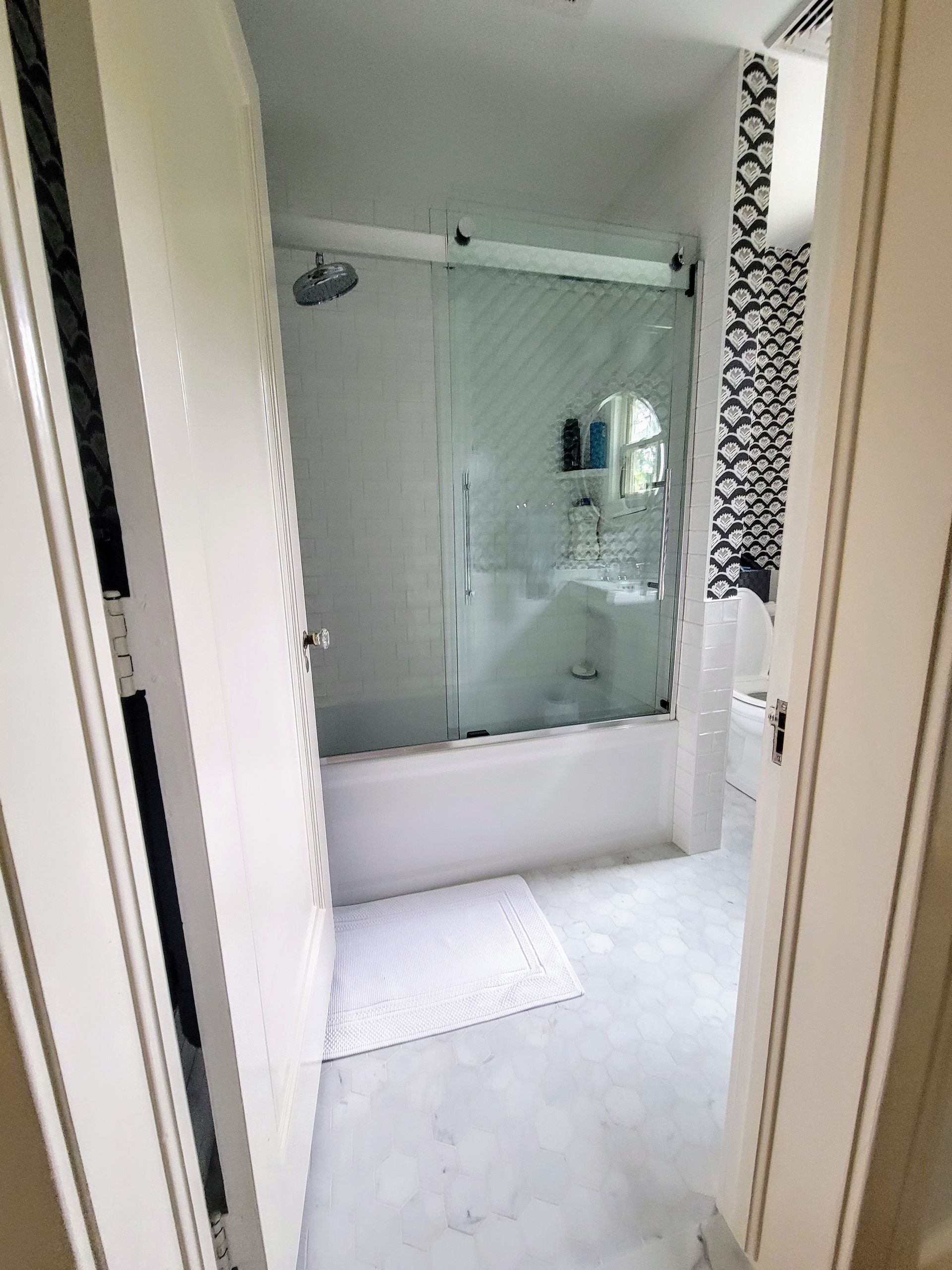 A bathroom with a tub , sink , shower and mirror.