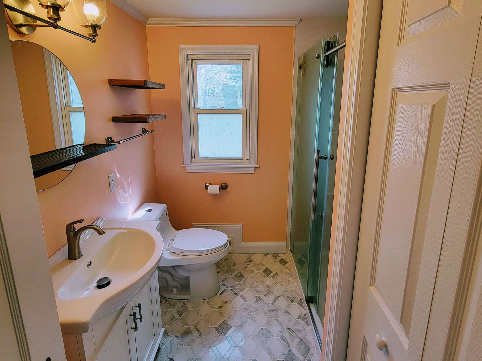 A bathroom with a toilet , sink , mirror and shower.