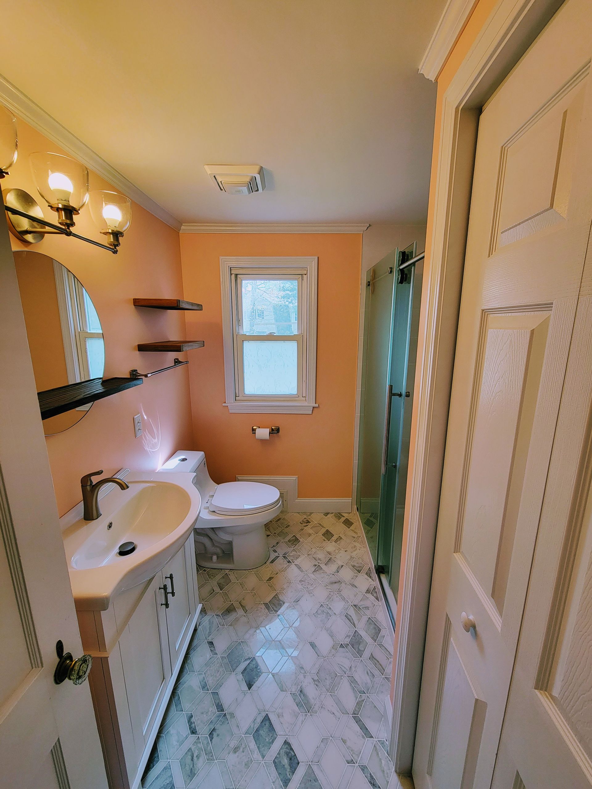 A bathroom with a toilet , sink , mirror and shower.