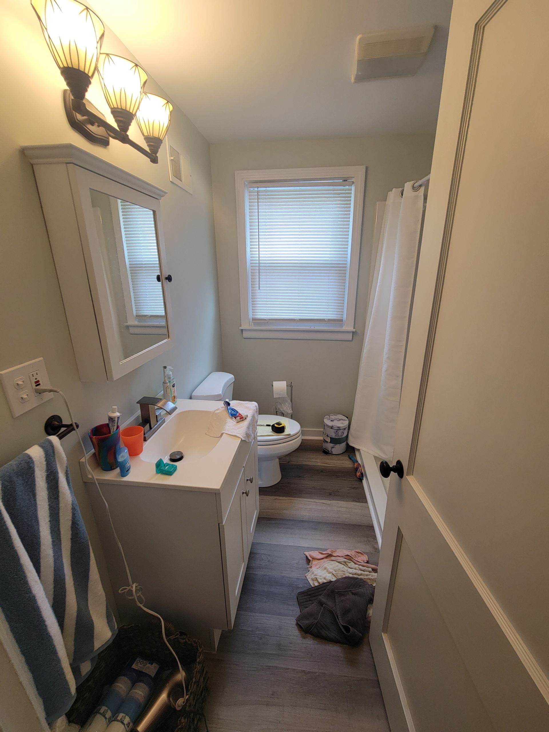 A bathroom with a sink , toilet , mirror and shower curtain.