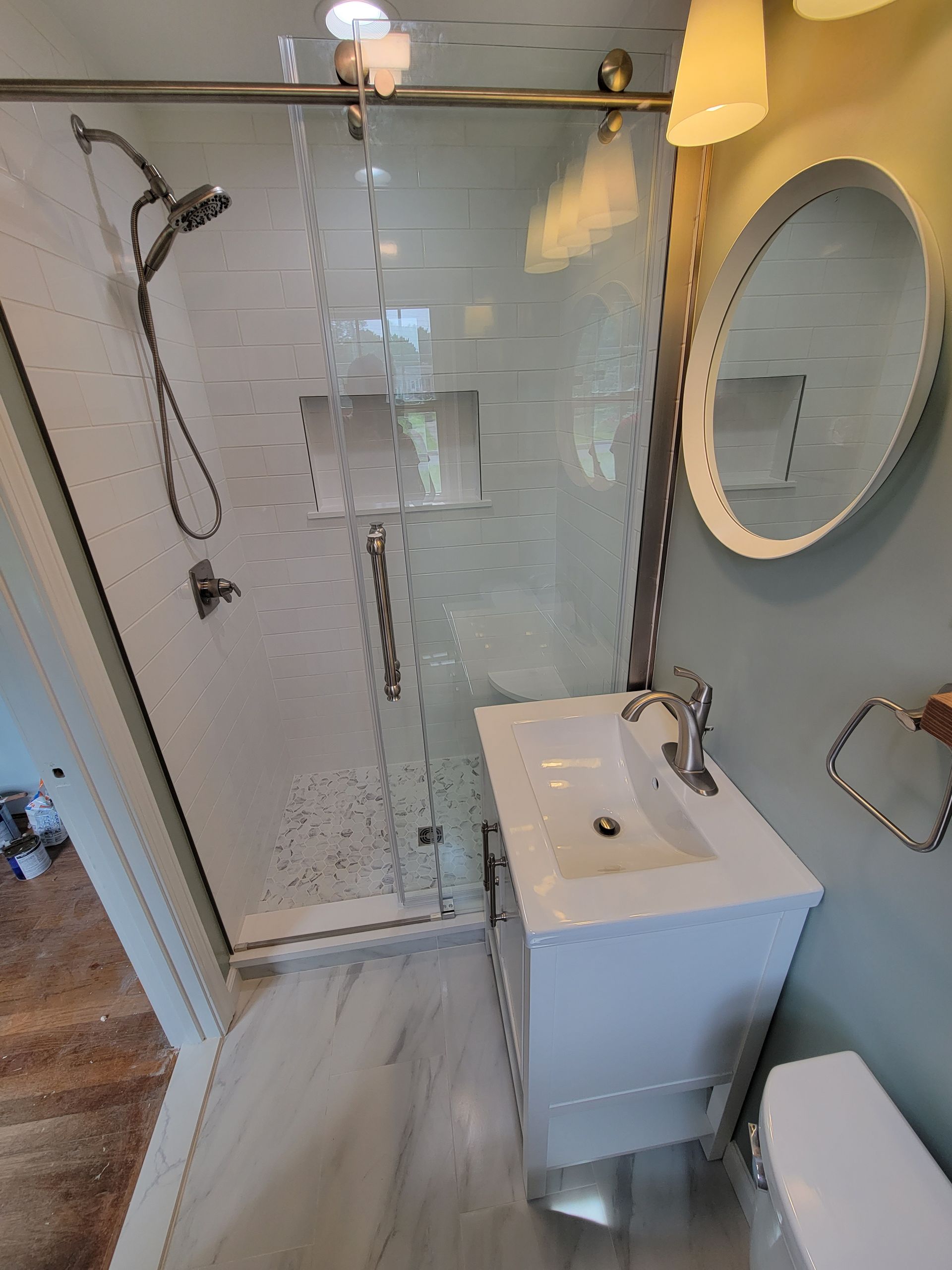 A bathroom with a sink , toilet , shower and mirror.