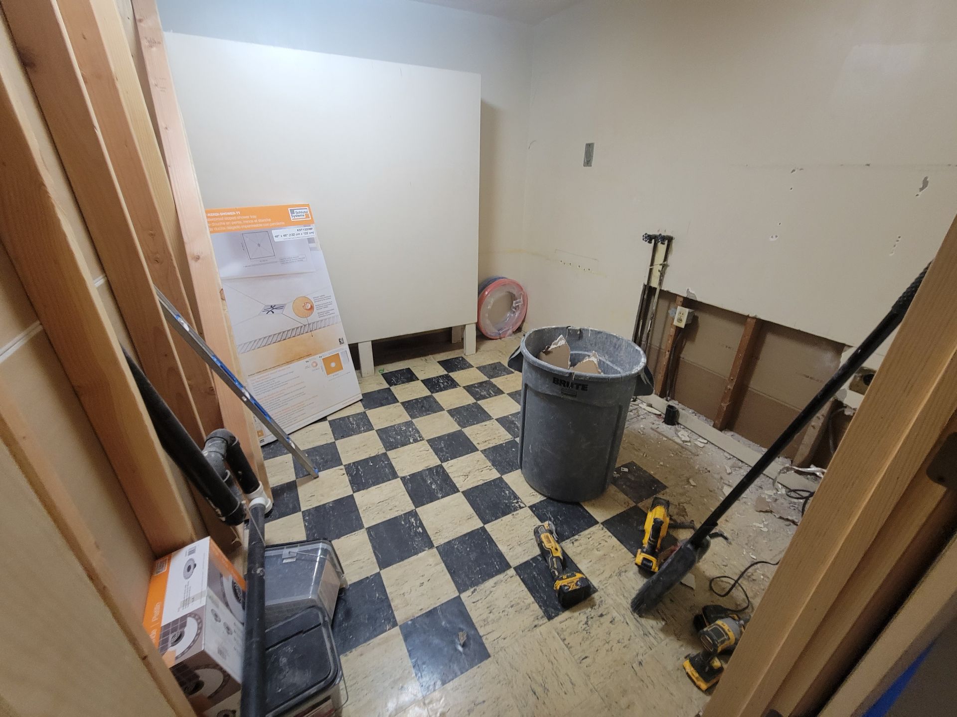 A room with a checkered floor and a trash can.