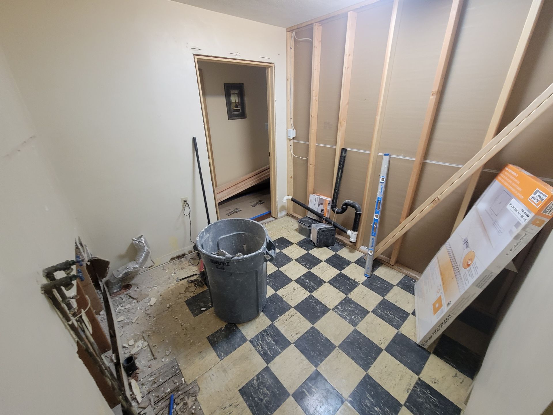 A room with a checkered floor and a bucket in it.