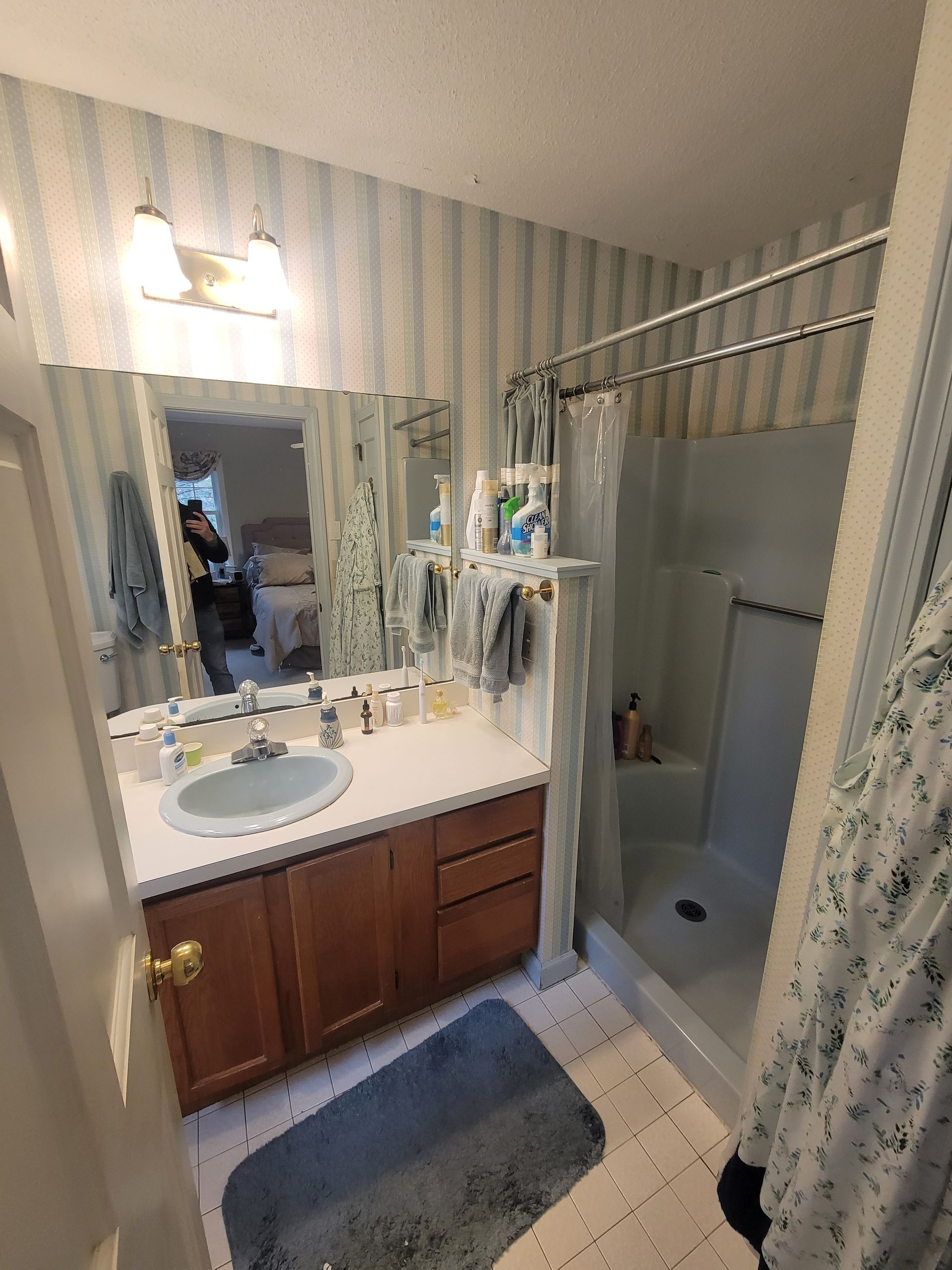 A bathroom with a sink , shower , and mirror.