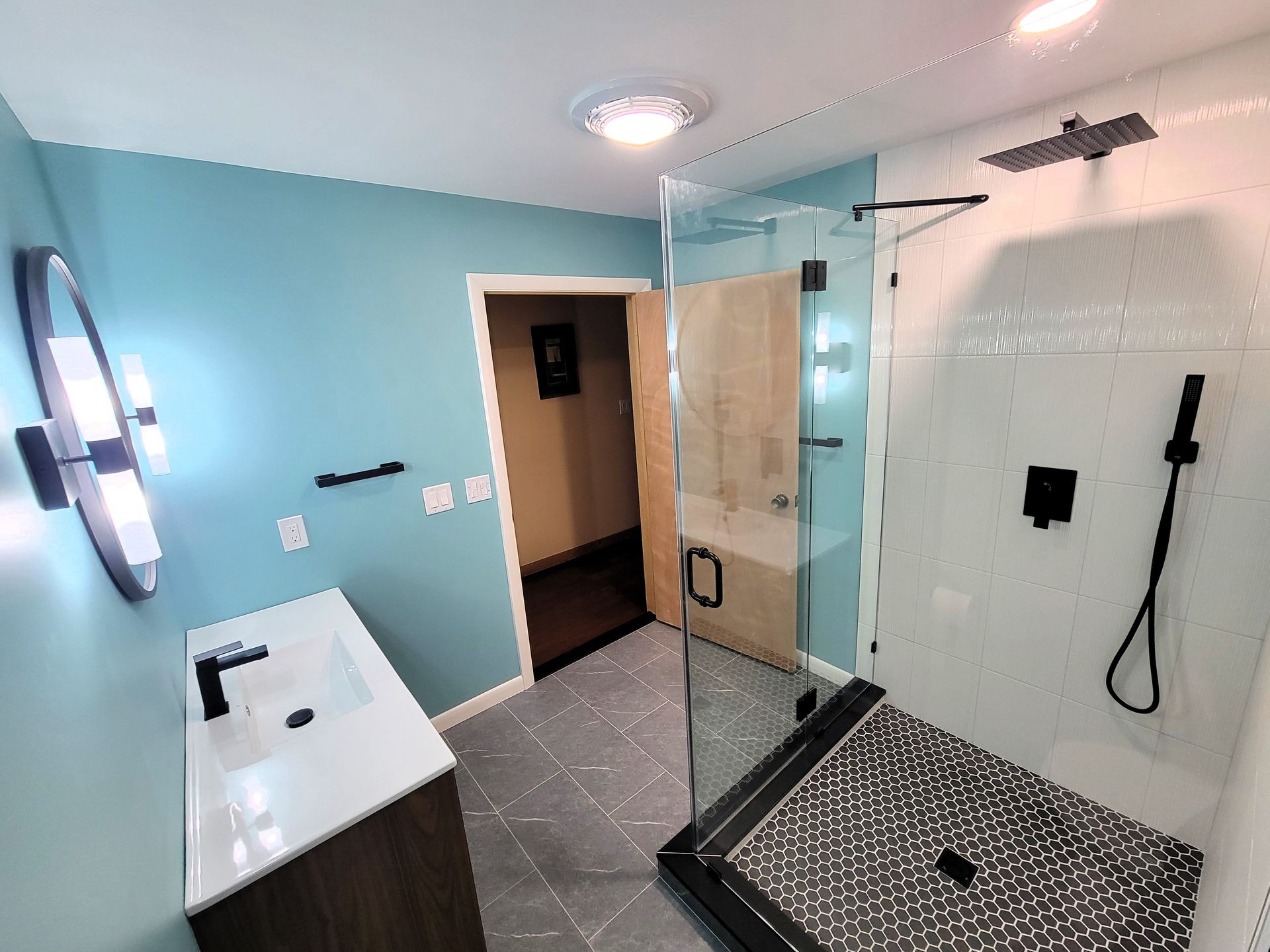 A bathroom with a walk in shower , sink and mirror.