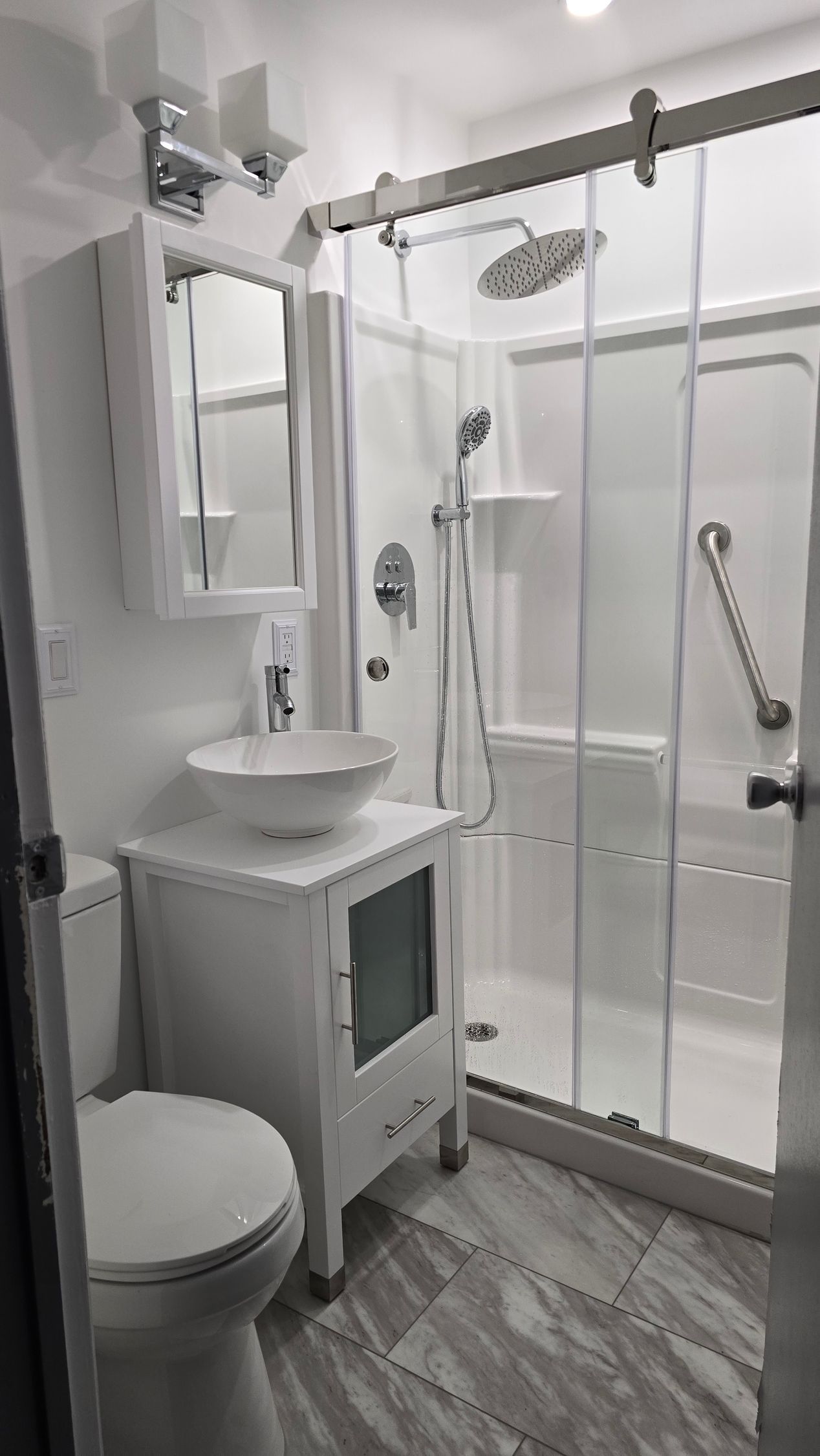 A bathroom with a toilet , sink , shower and mirror.