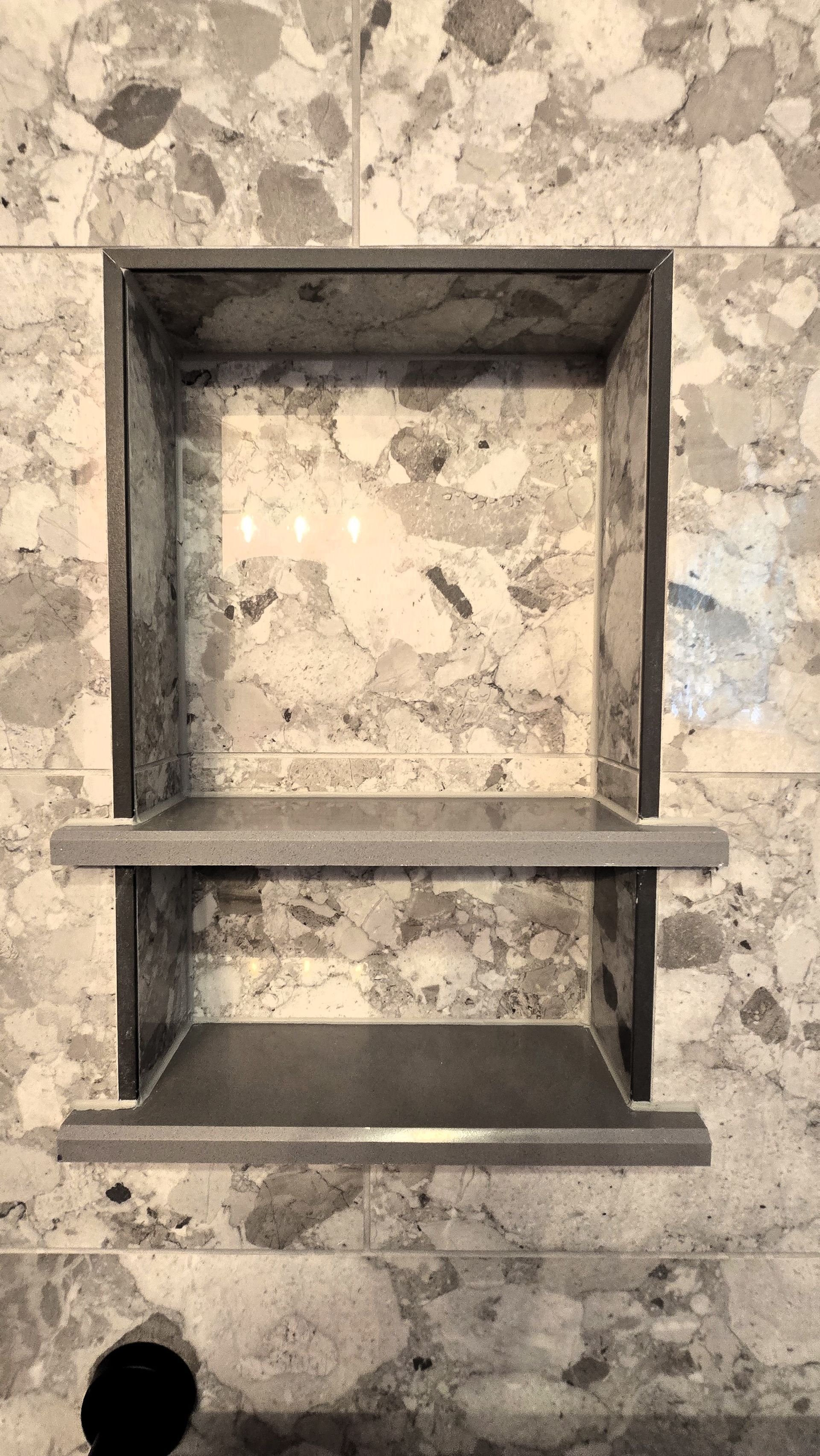 Recessed rectangular shelf in a mottled stone wall. A single shelf divides the opening.