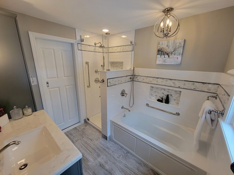 Bathroom with a white bathtub in Bristol, CT, glass shower, white door, and grey floor.