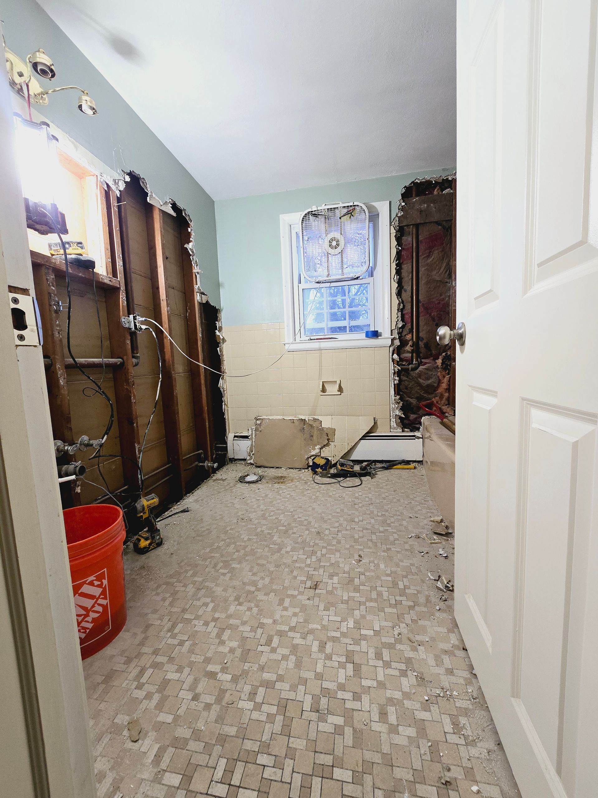 A bathroom under construction with a window and a bucket on the floor.