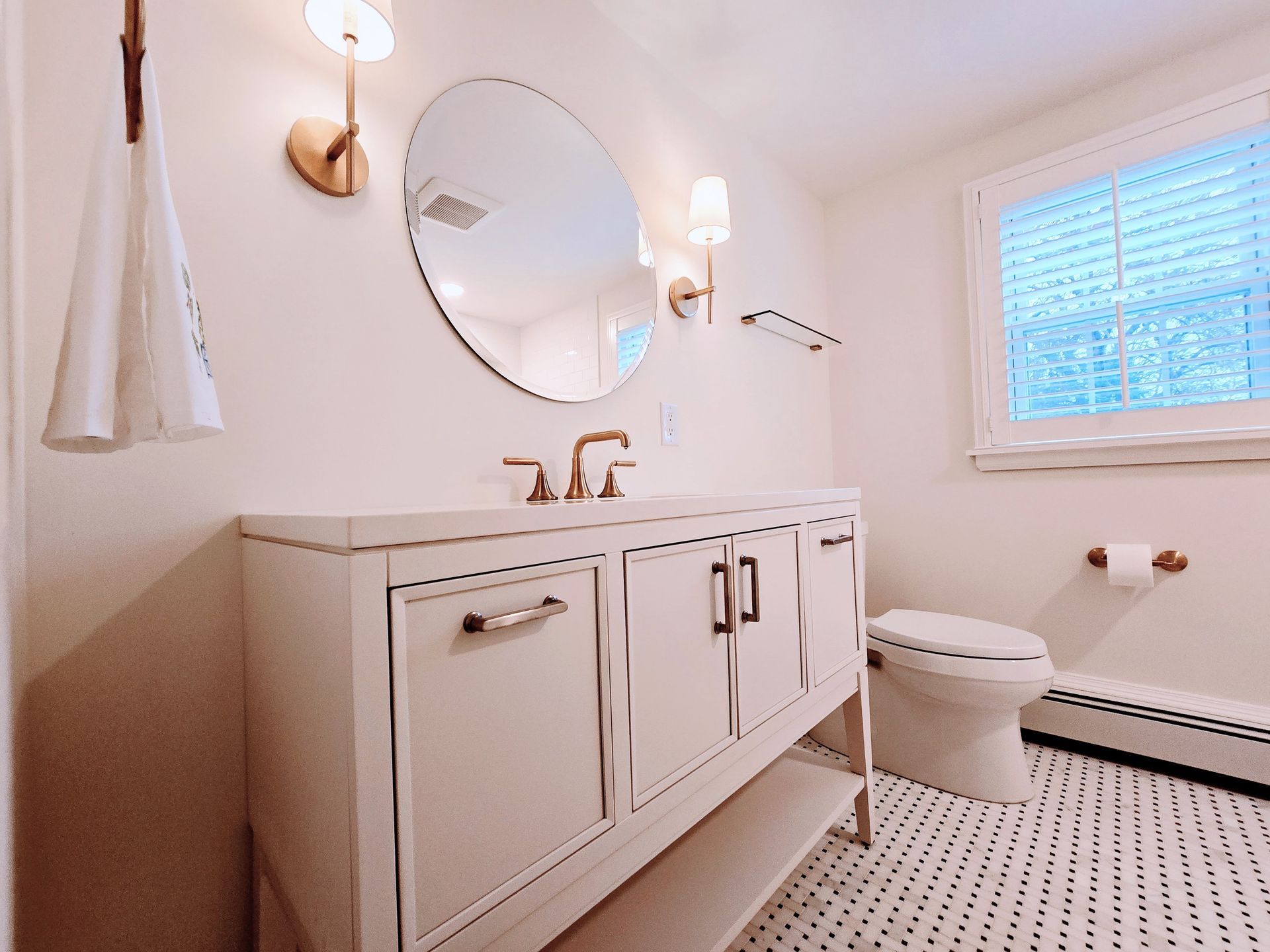 A bathroom with a sink , toilet , mirror and window.