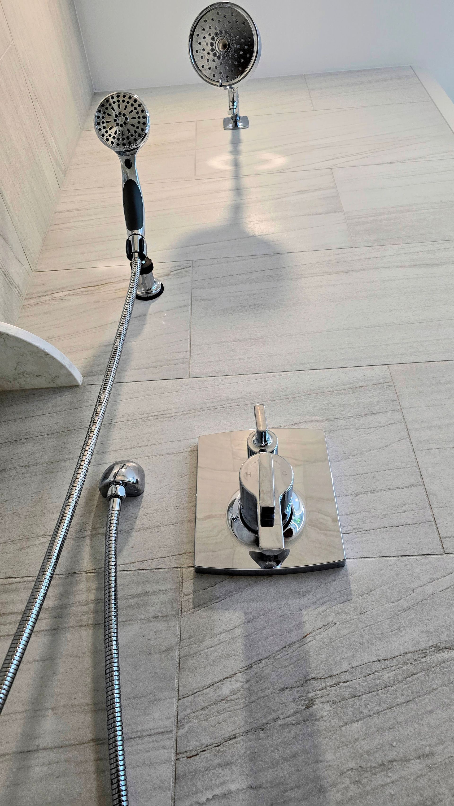 Chrome shower fixtures against a textured stone wall.