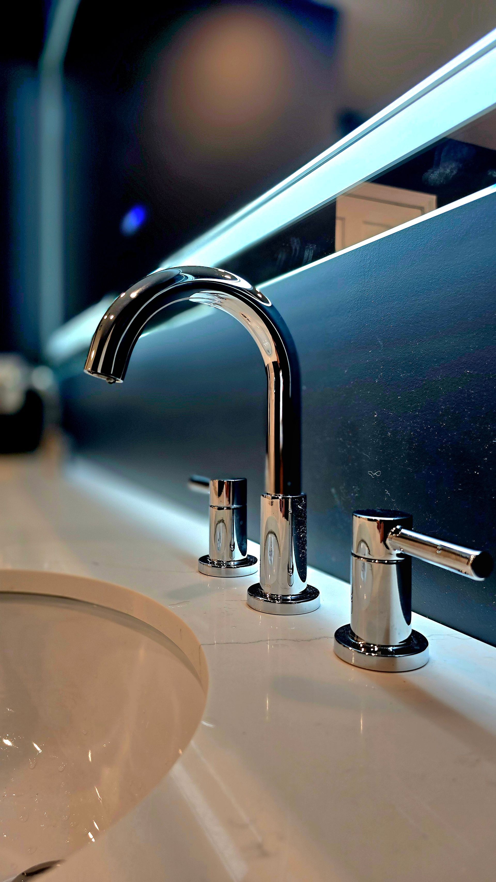 Shiny chrome faucet with two lever handles on a white countertop.