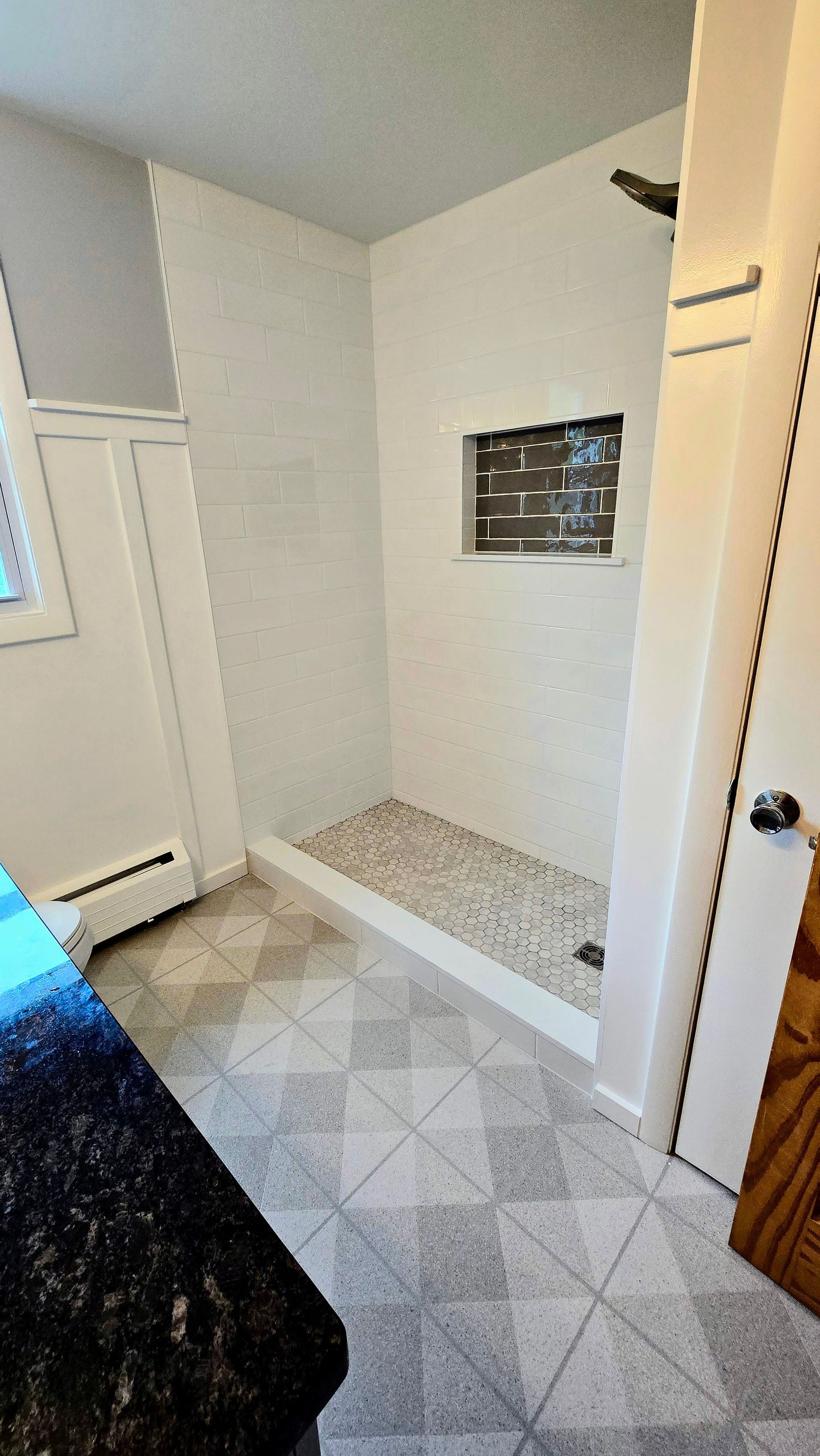 A bathroom with a walk in shower and a black counter top.