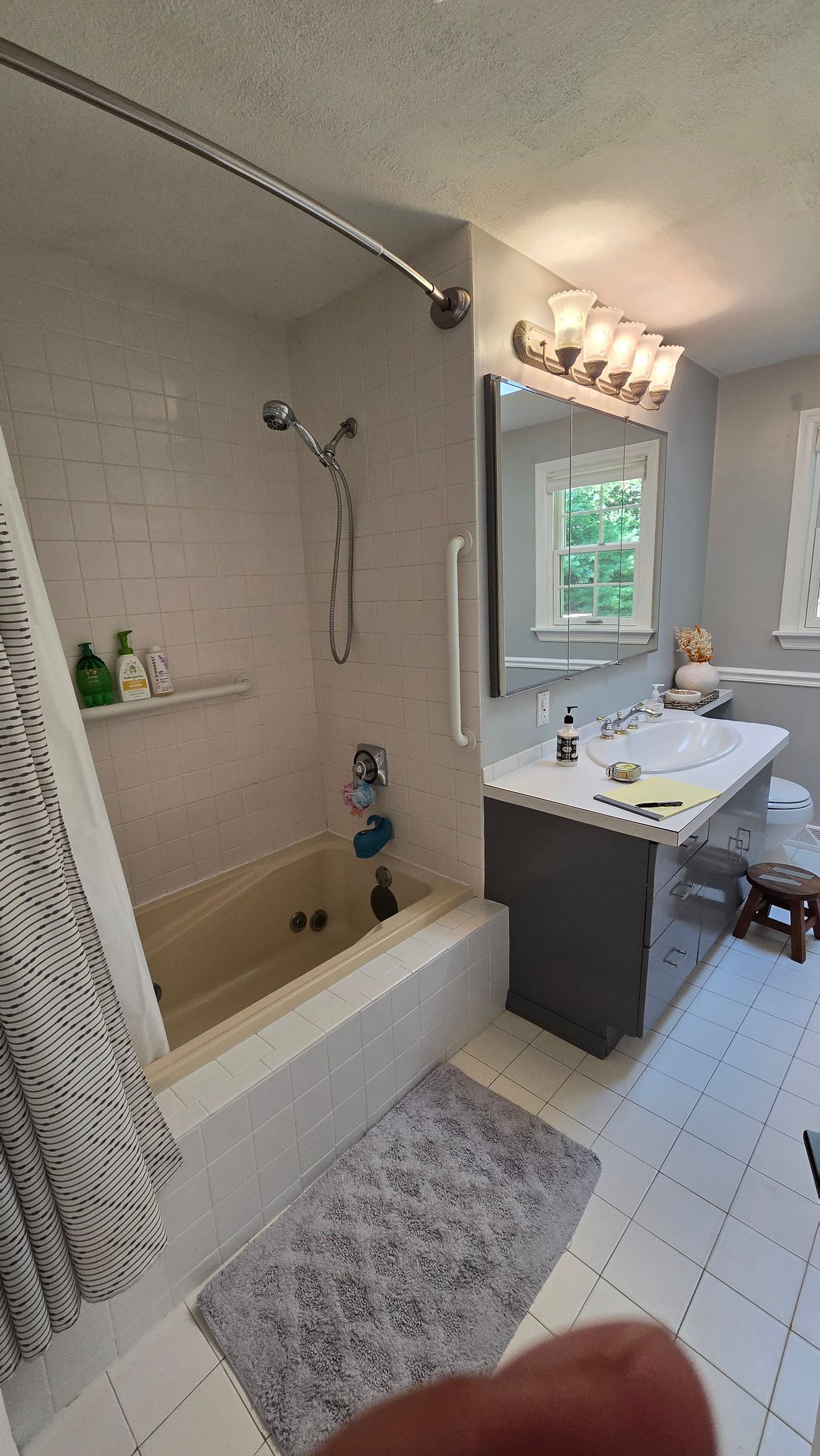 Bathroom with a tub and shower, vanity, and gray and white color scheme.