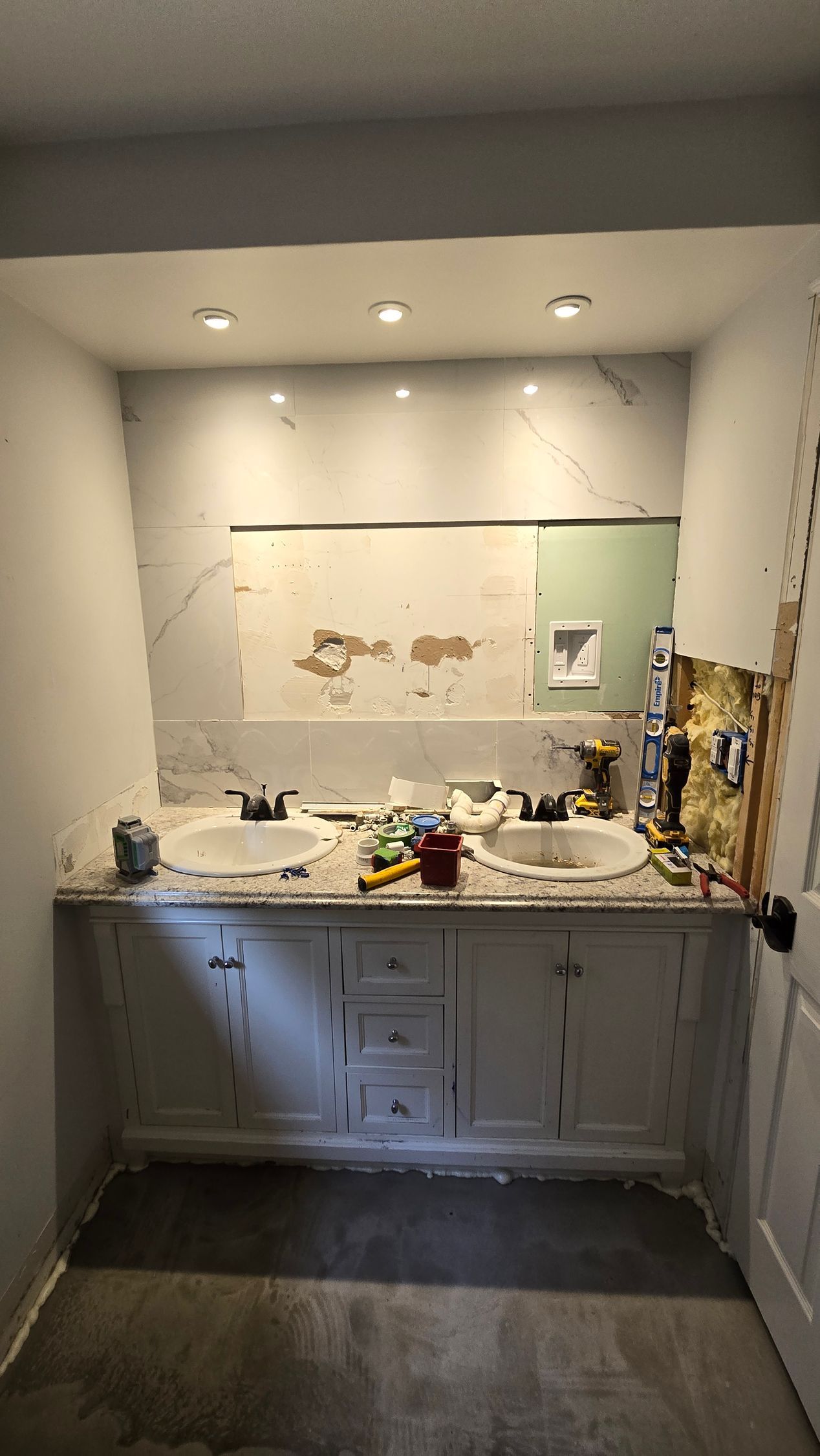 A bathroom under construction with two sinks and a mirror.