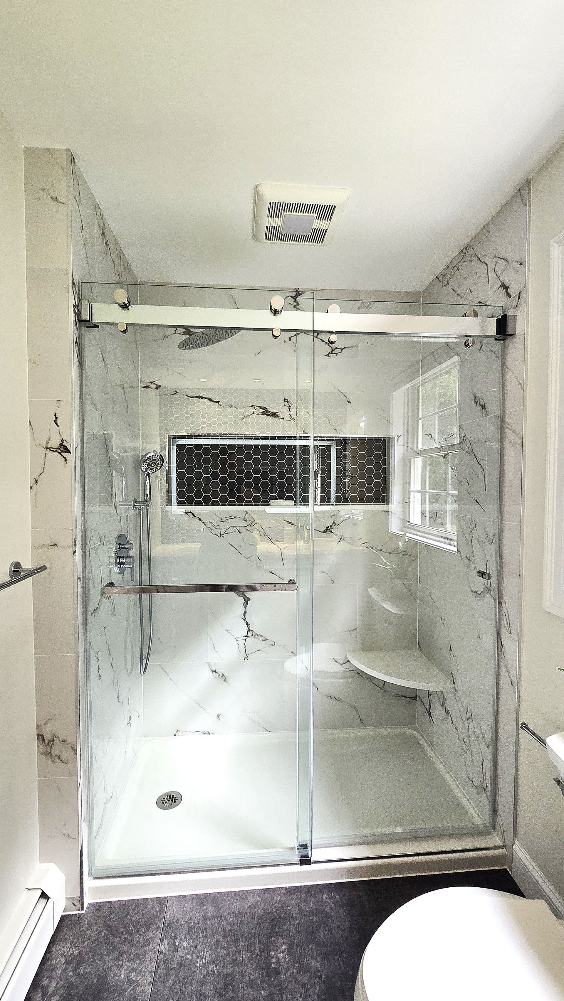 A bathroom with a sliding glass shower door and a toilet.