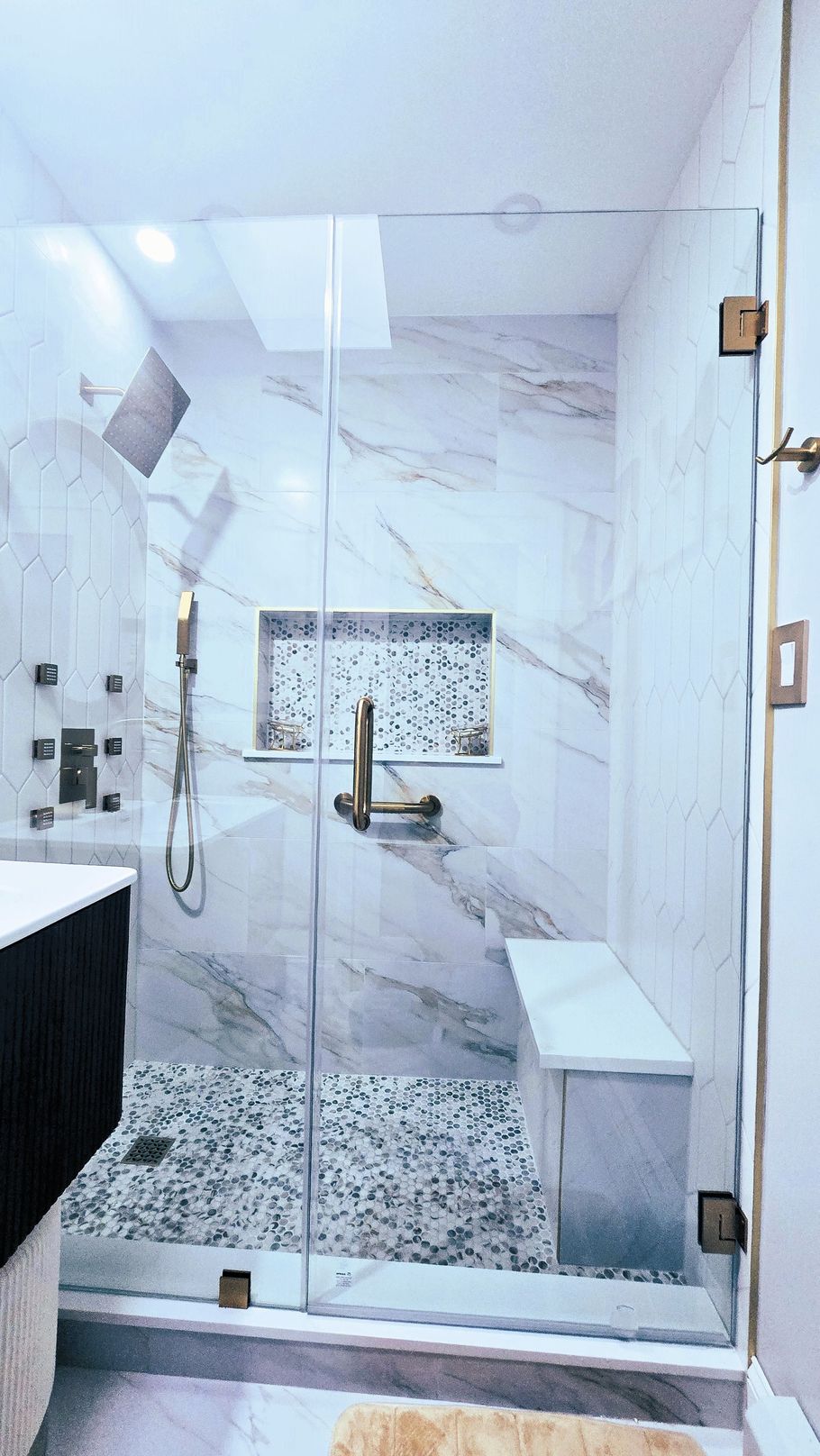 A bathroom with a walk in shower and a bench.