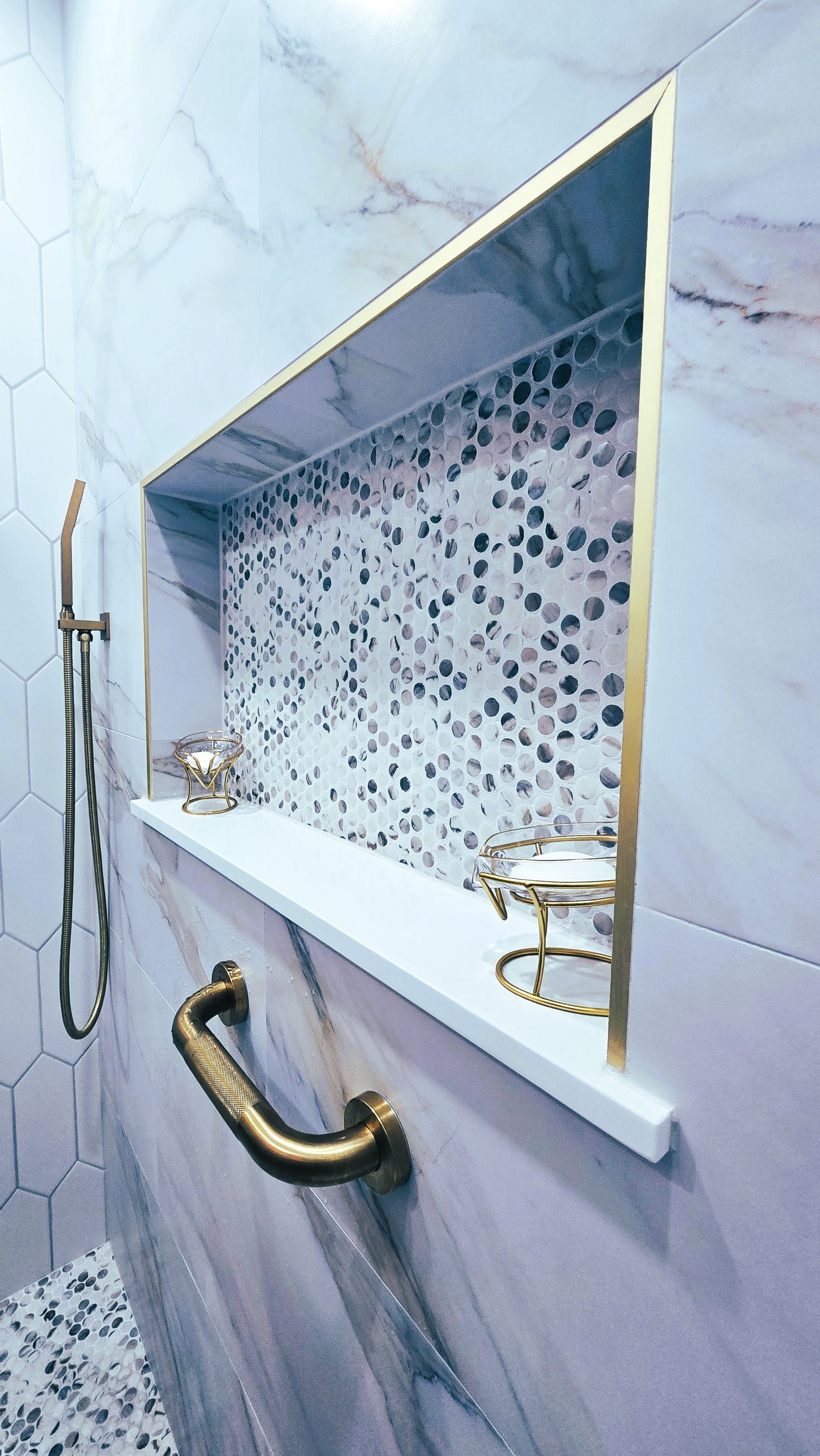 A bathroom with a shower and a shelf with a gold handle.