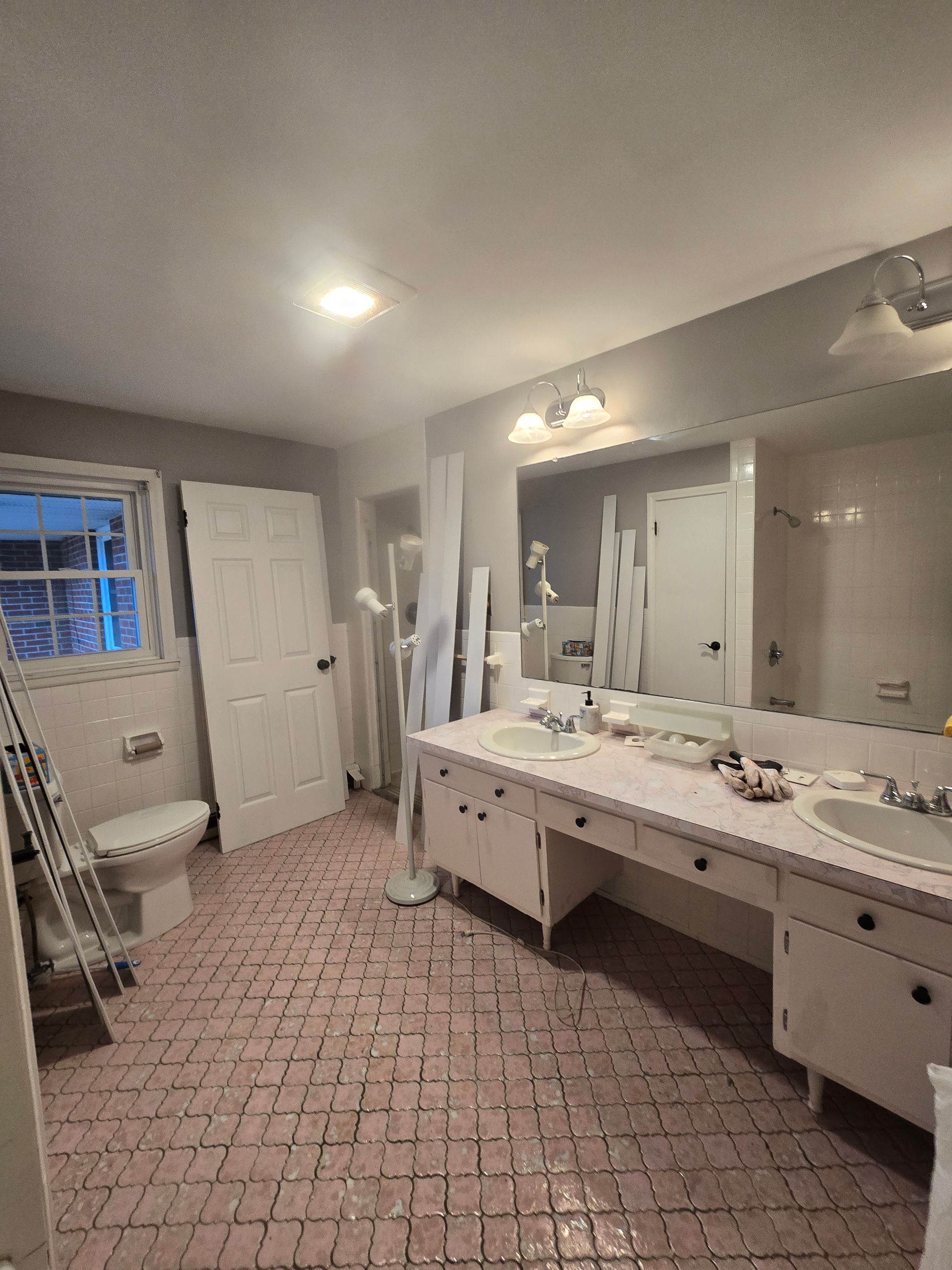 A bathroom with two sinks , a toilet , and a large mirror.