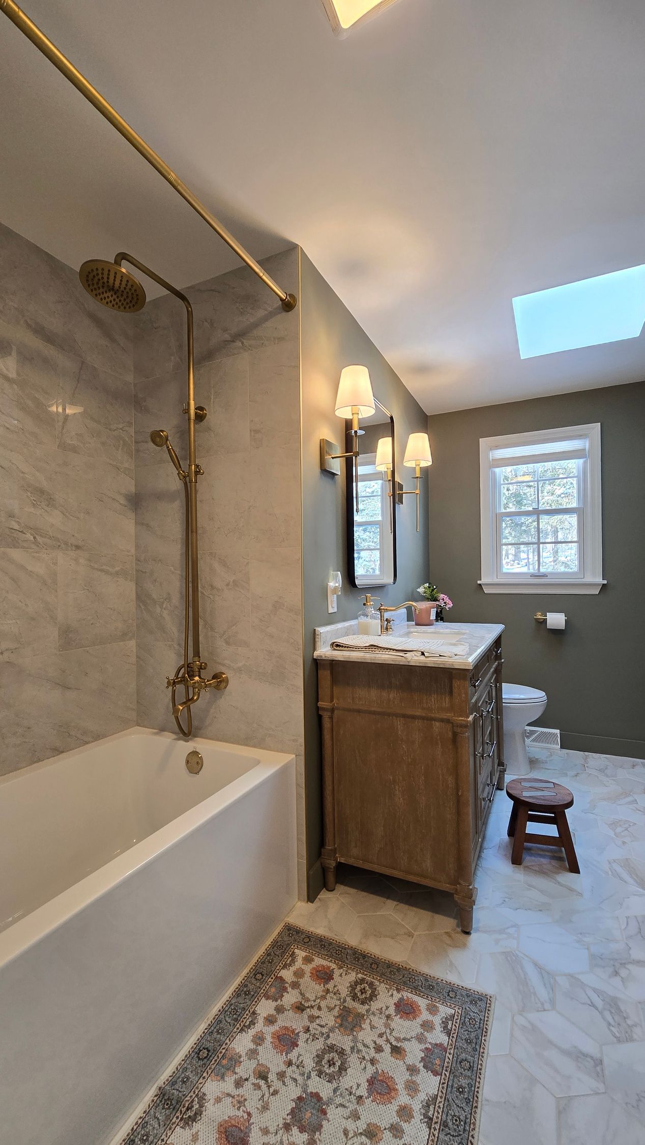 A bathroom with a bathtub , sink , mirror and rug.