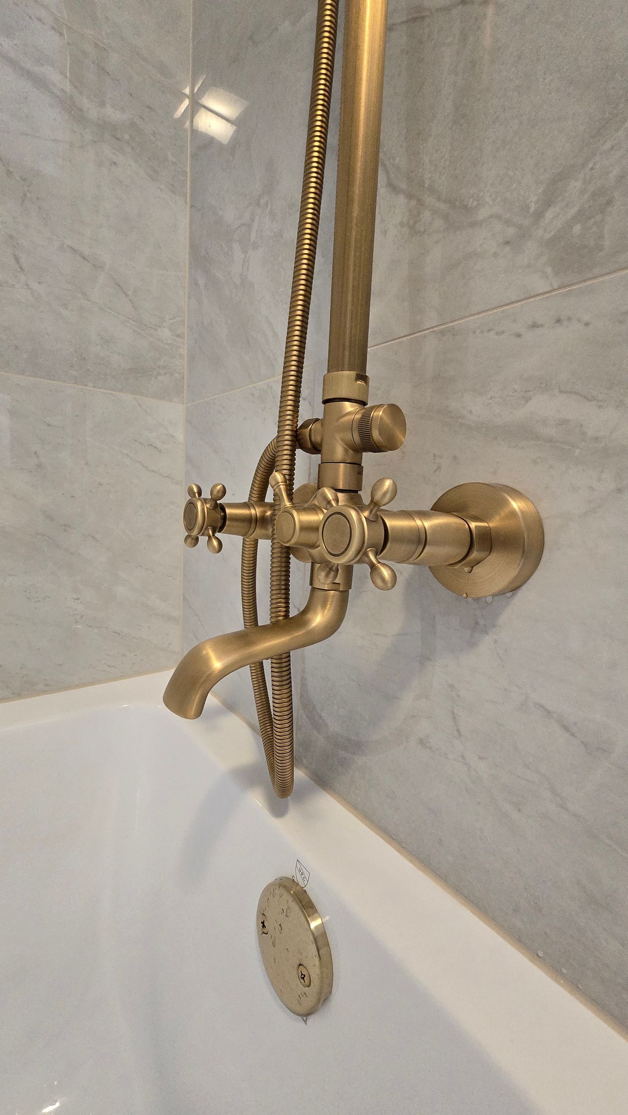 A bathtub with a brass shower head attached to it.