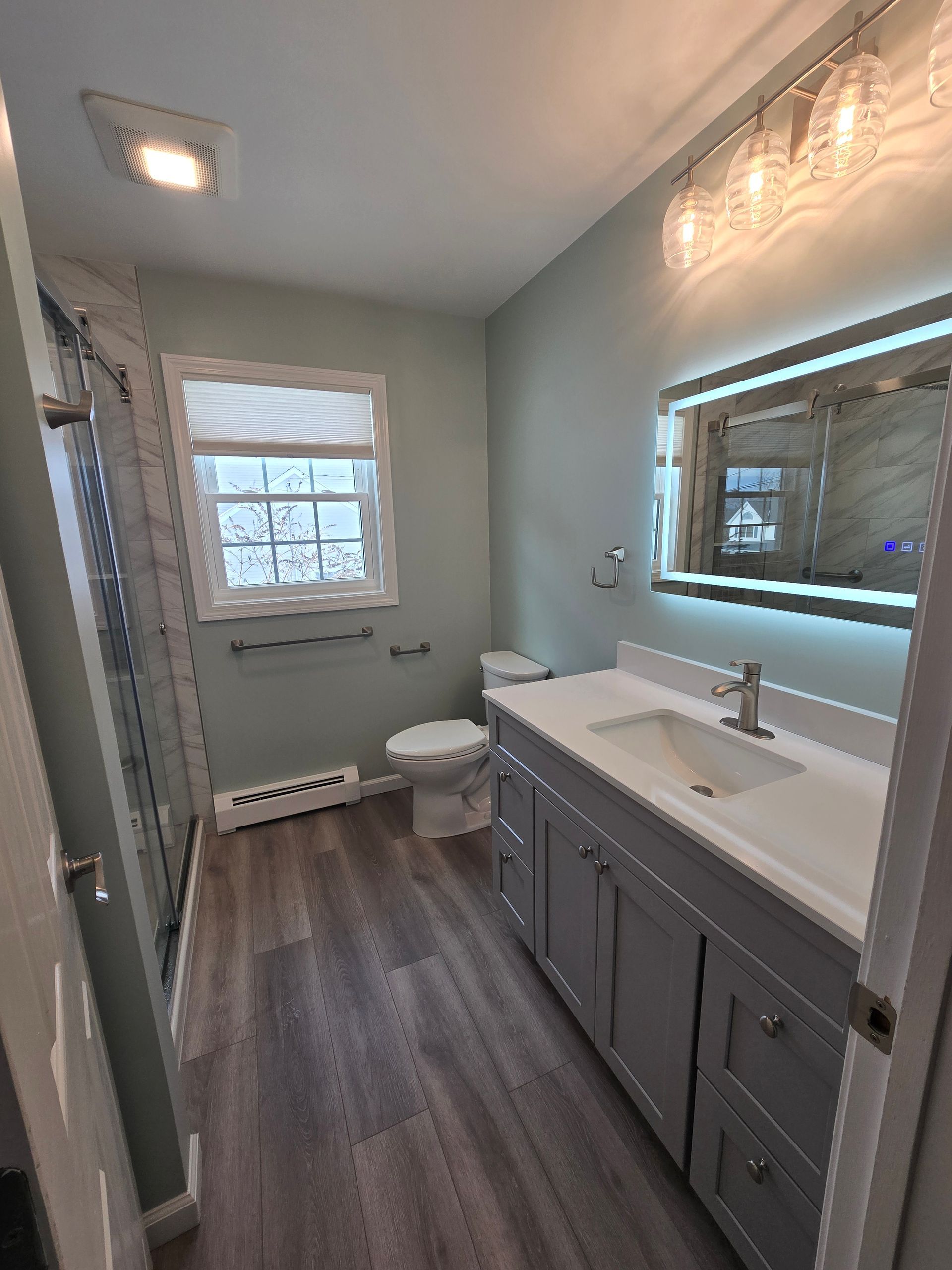 A bathroom with a bathtub , sink , mirror and rug.