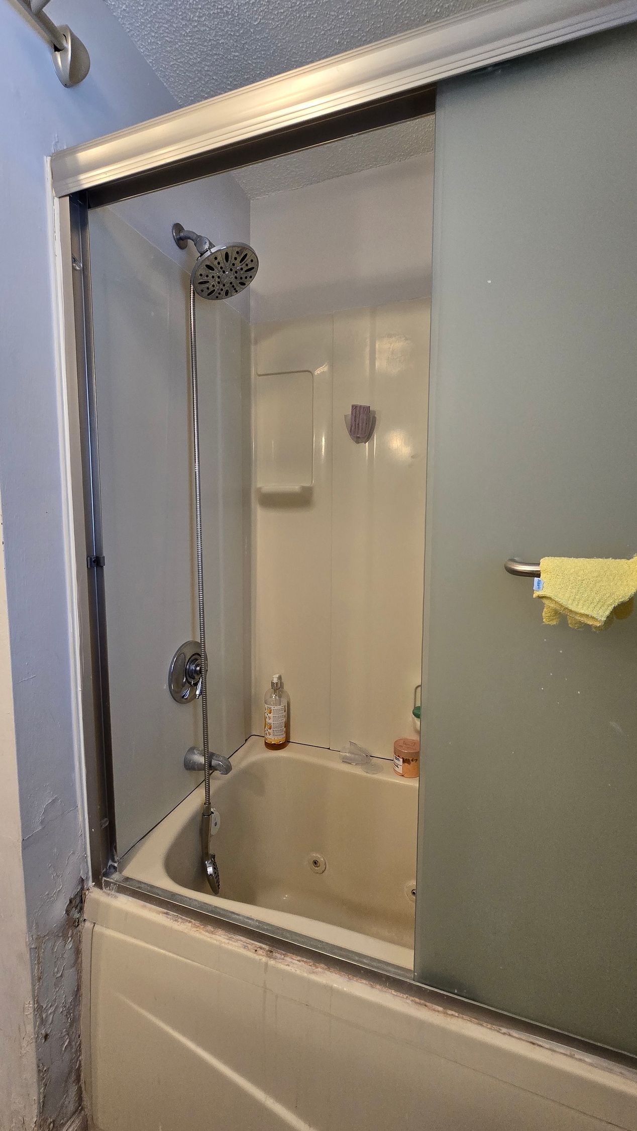 Shower with sliding glass doors. Tub is white, with a chrome shower head.