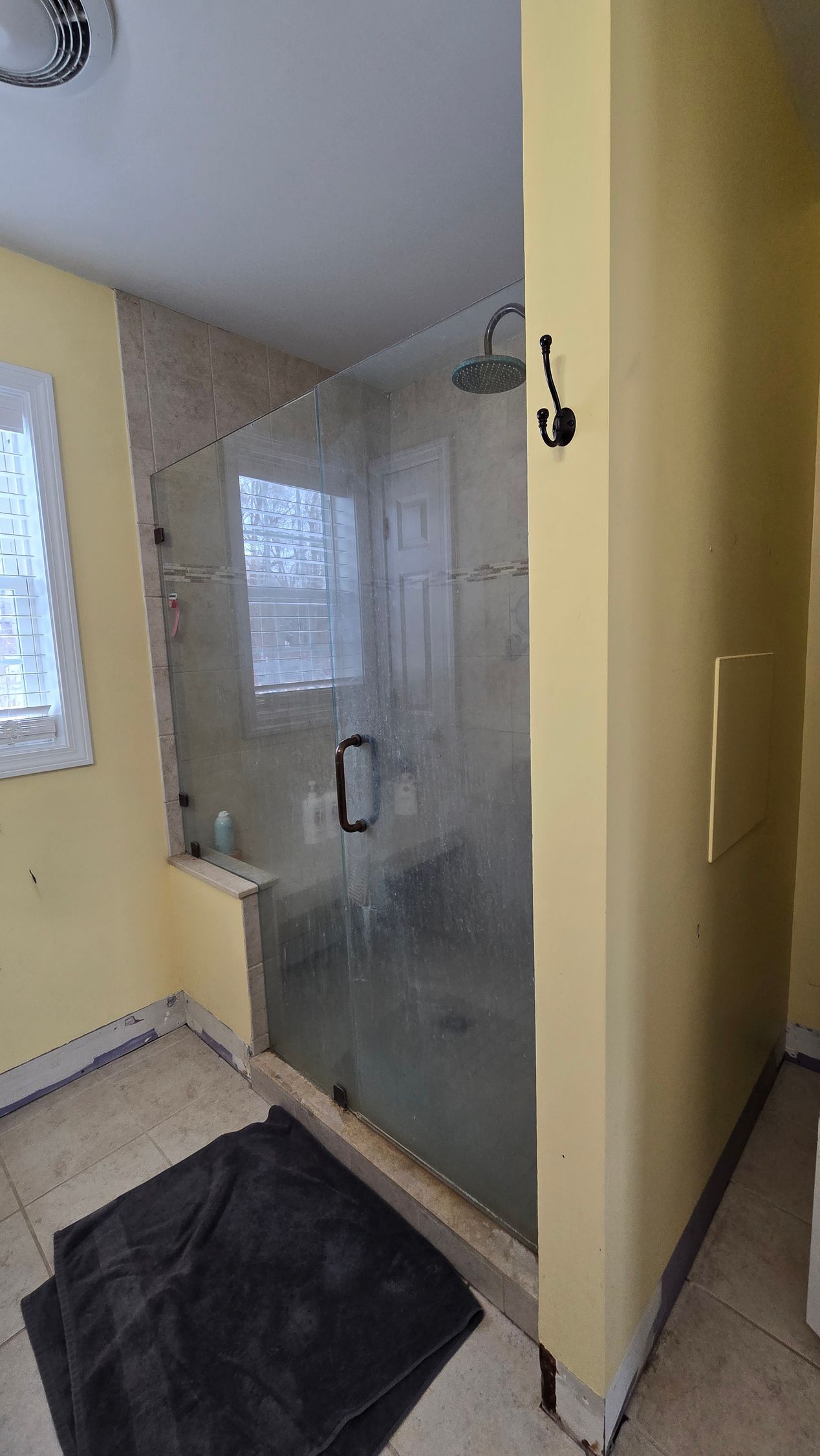 A bathroom with a walk in shower and a window.