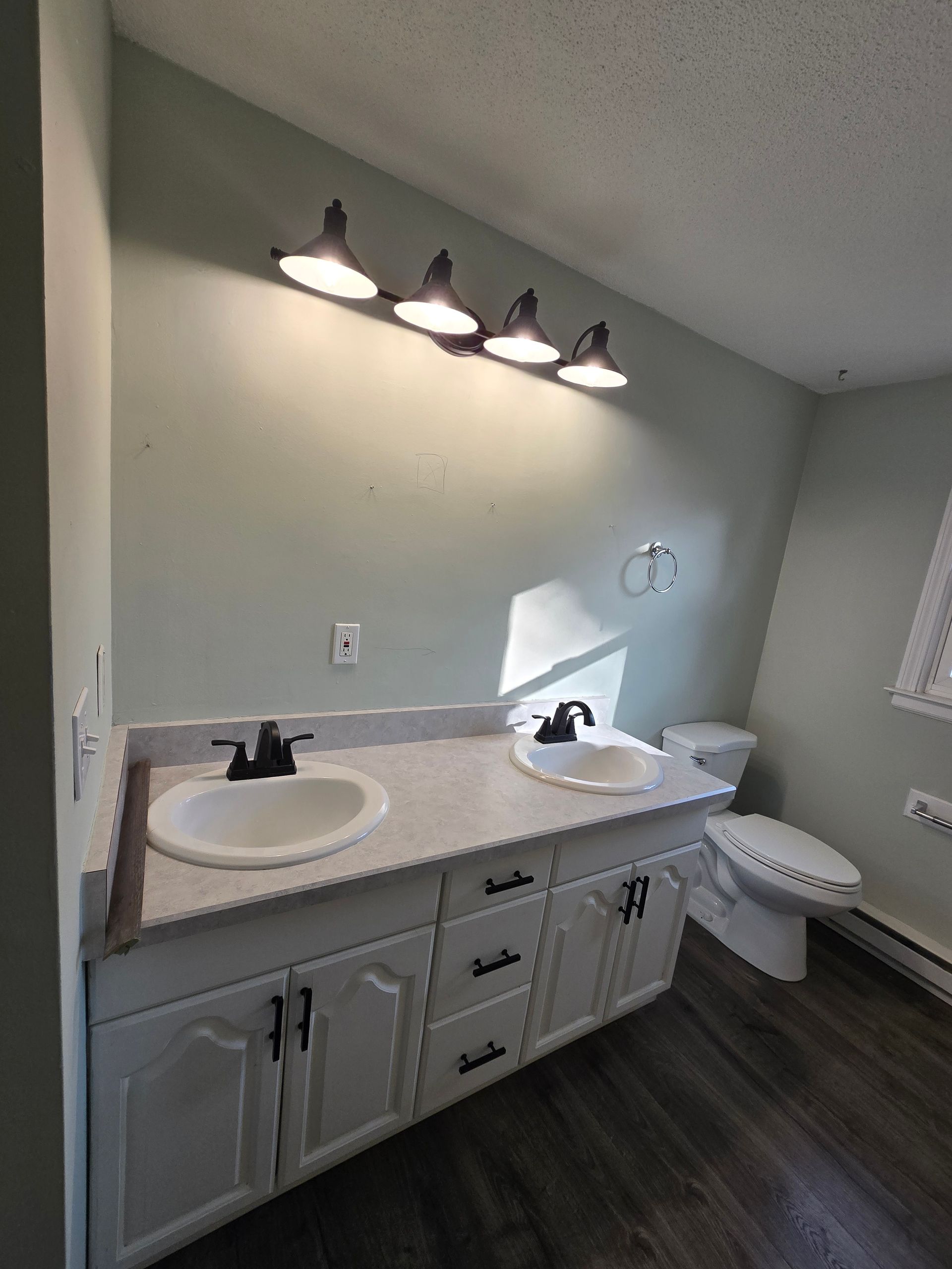 A bathroom with a sink , toilet , and window.