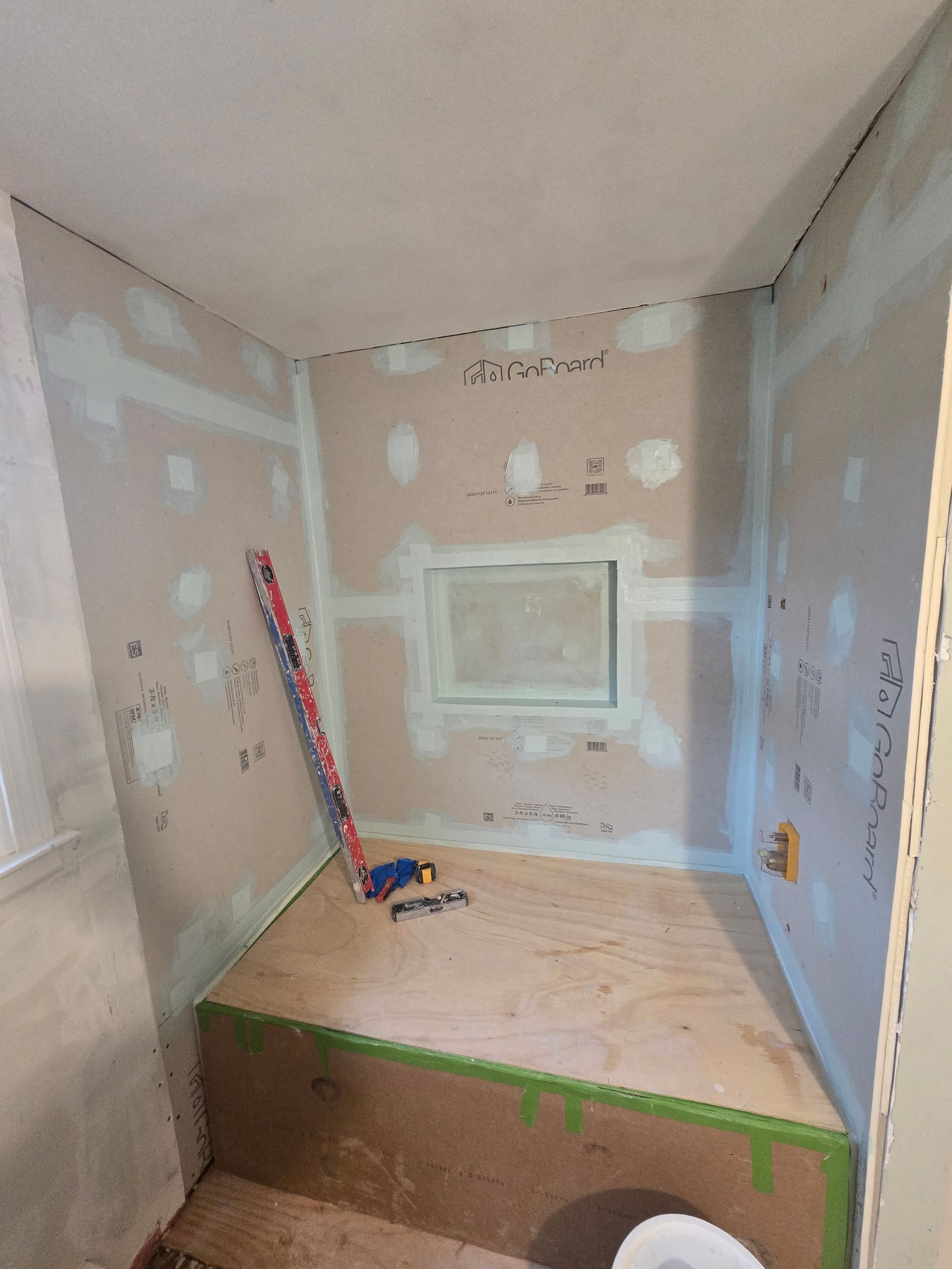 A bathroom under construction with a toilet and a measuring tape.