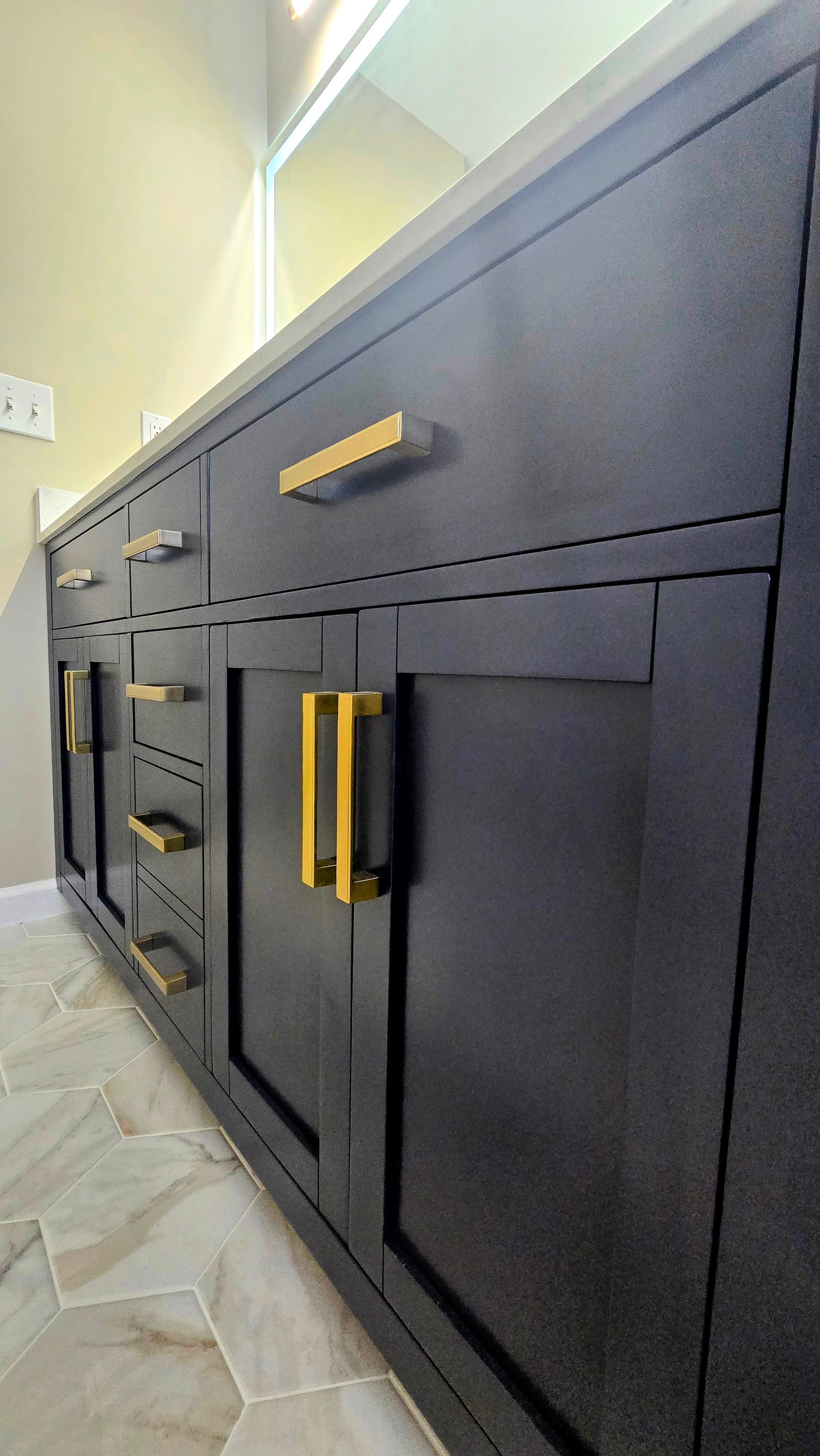 Dark gray bathroom vanity with gold hardware.