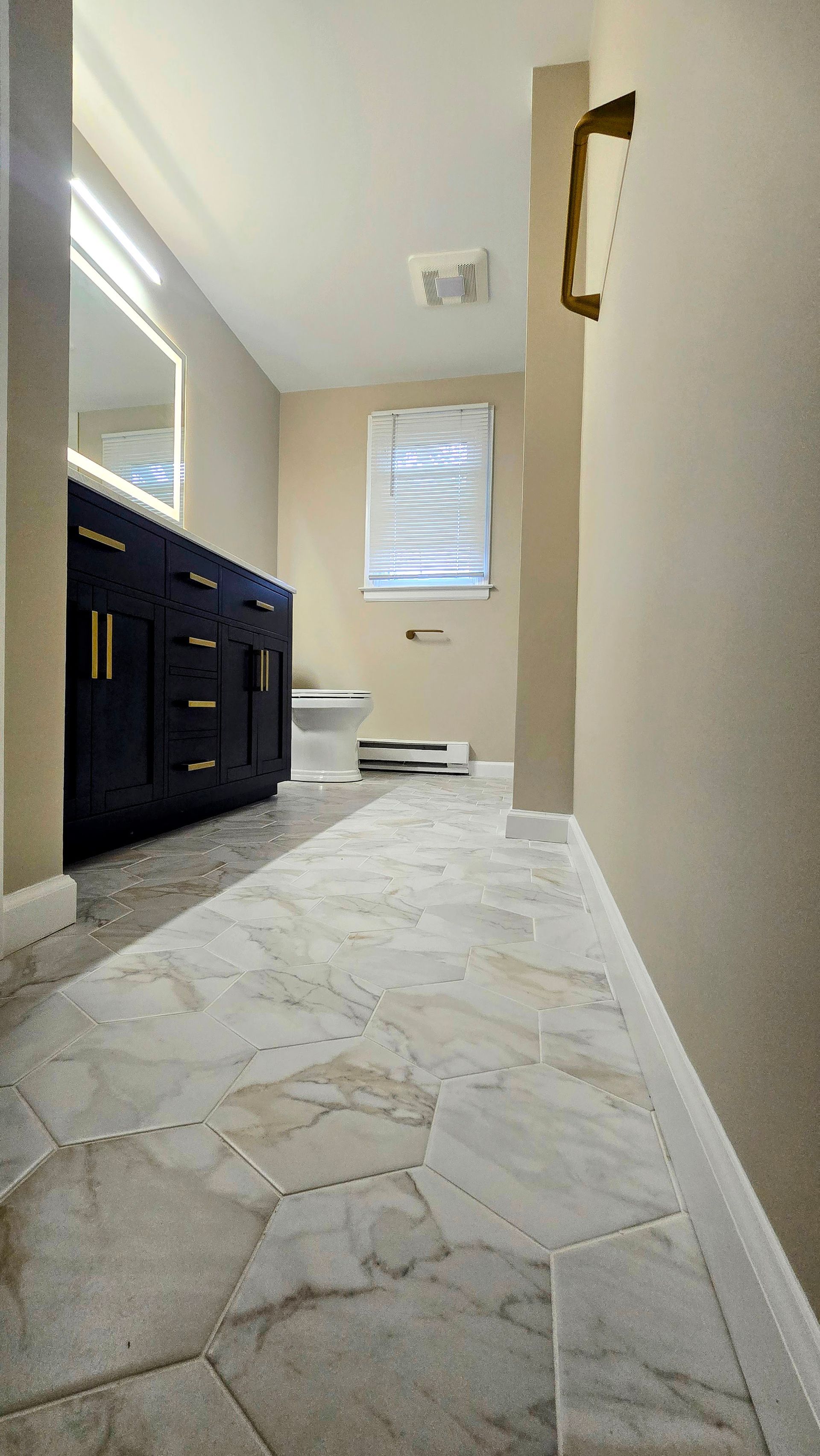 A bathroom with a marble floor , a sink , a mirror and a window.