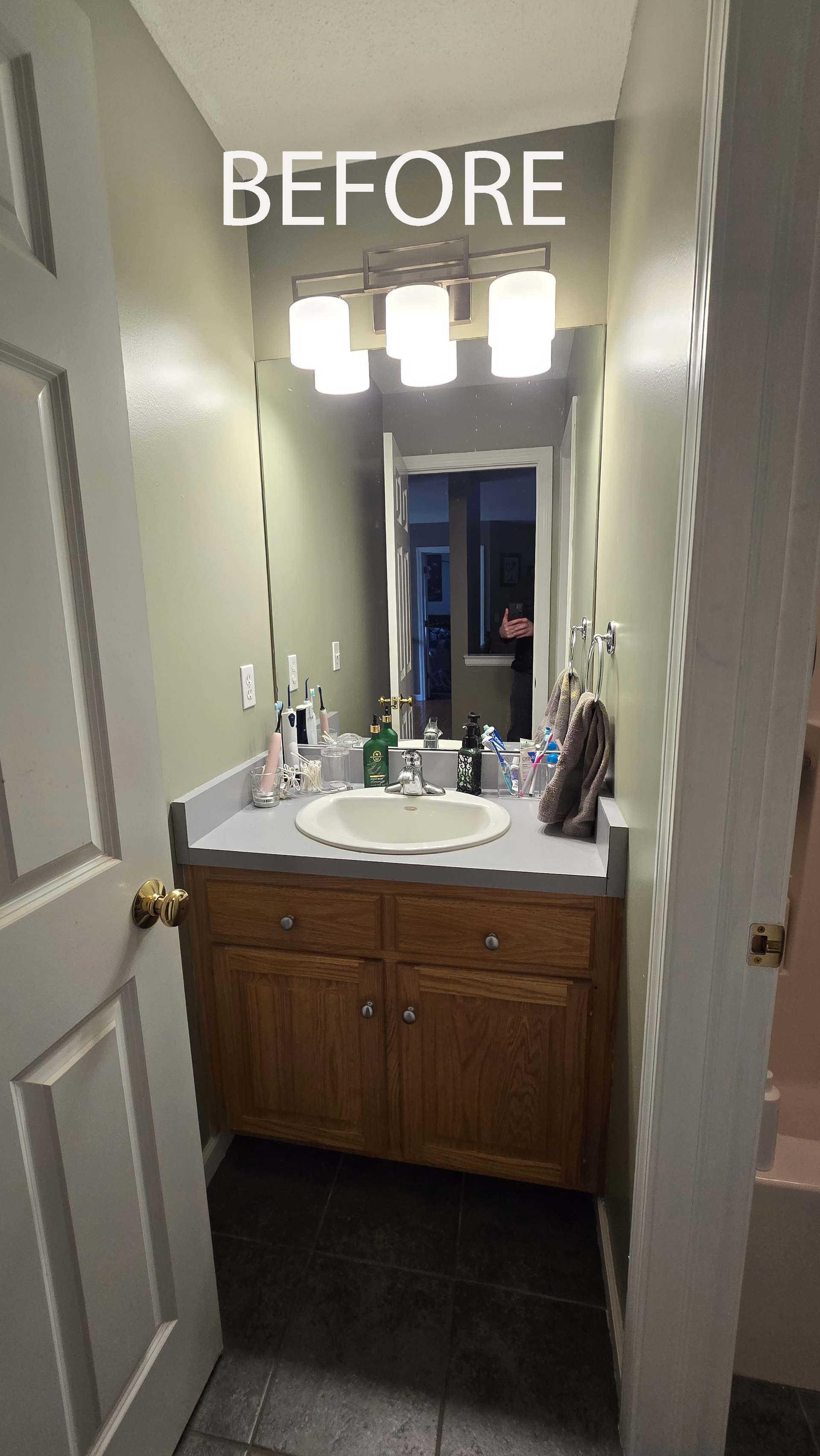 Small bathroom with a wood vanity, mirror, sink, and overhead lights.