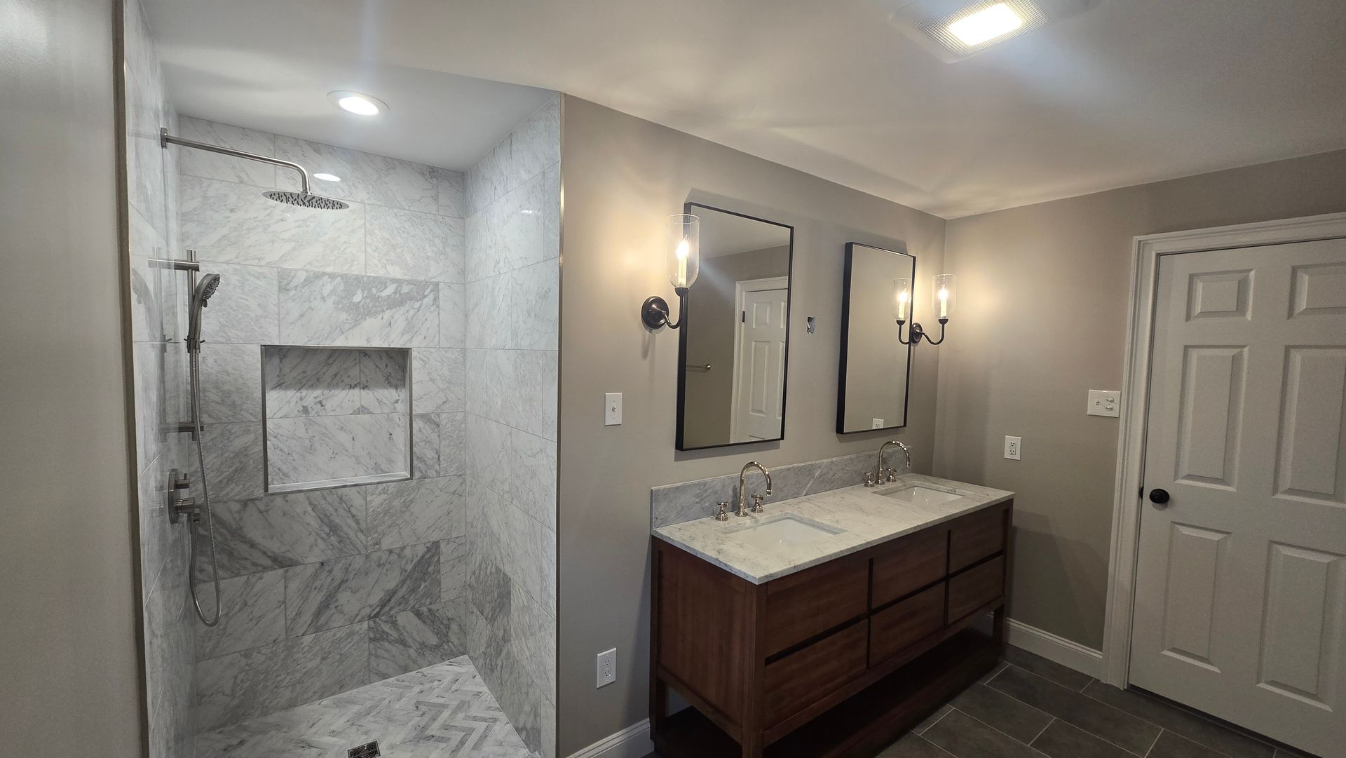 A bathroom with two sinks and a walk in shower.