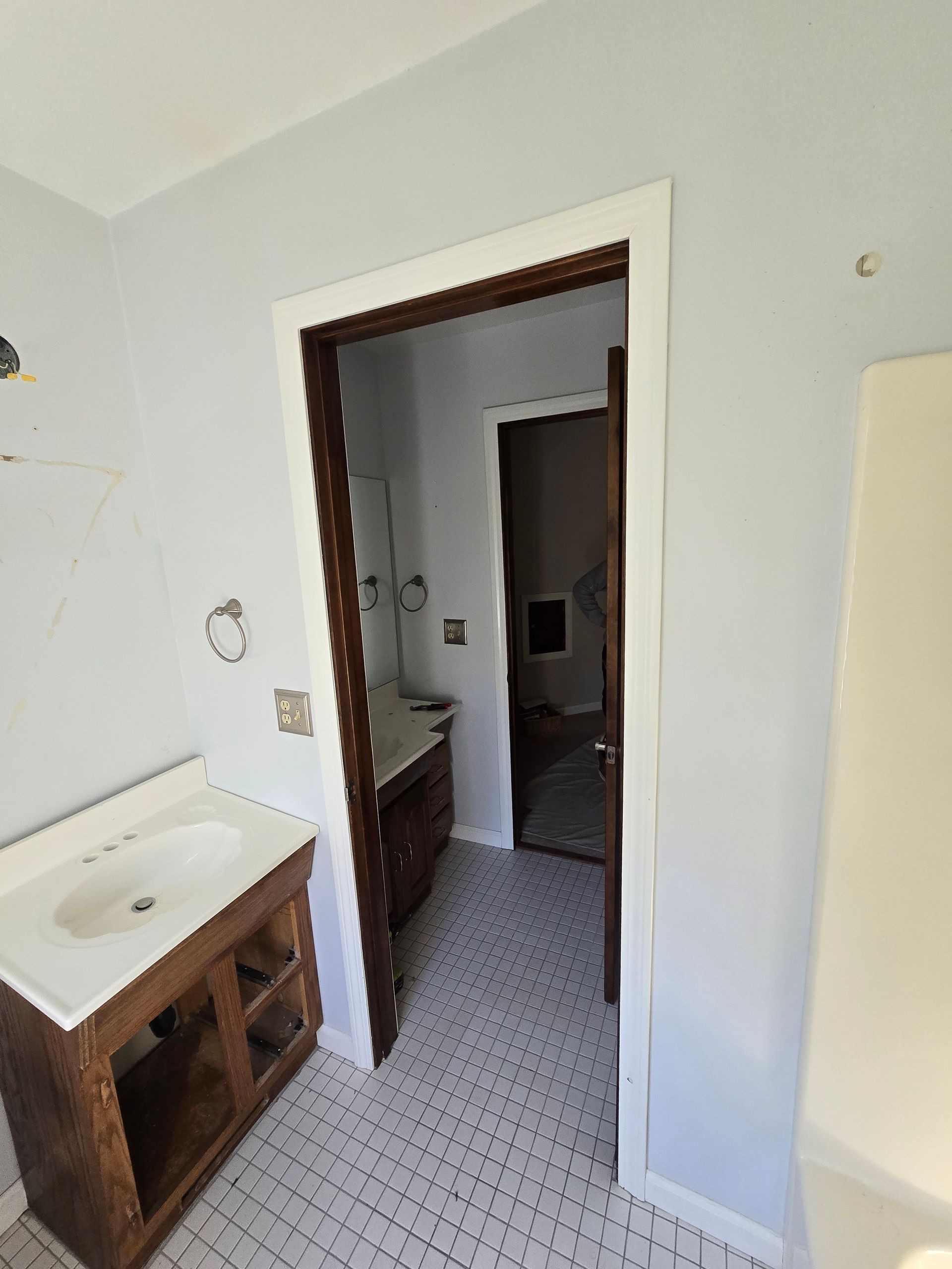 Bathroom interior with light blue walls, a dark wood door frame, and a sink with a dark wood vanity.