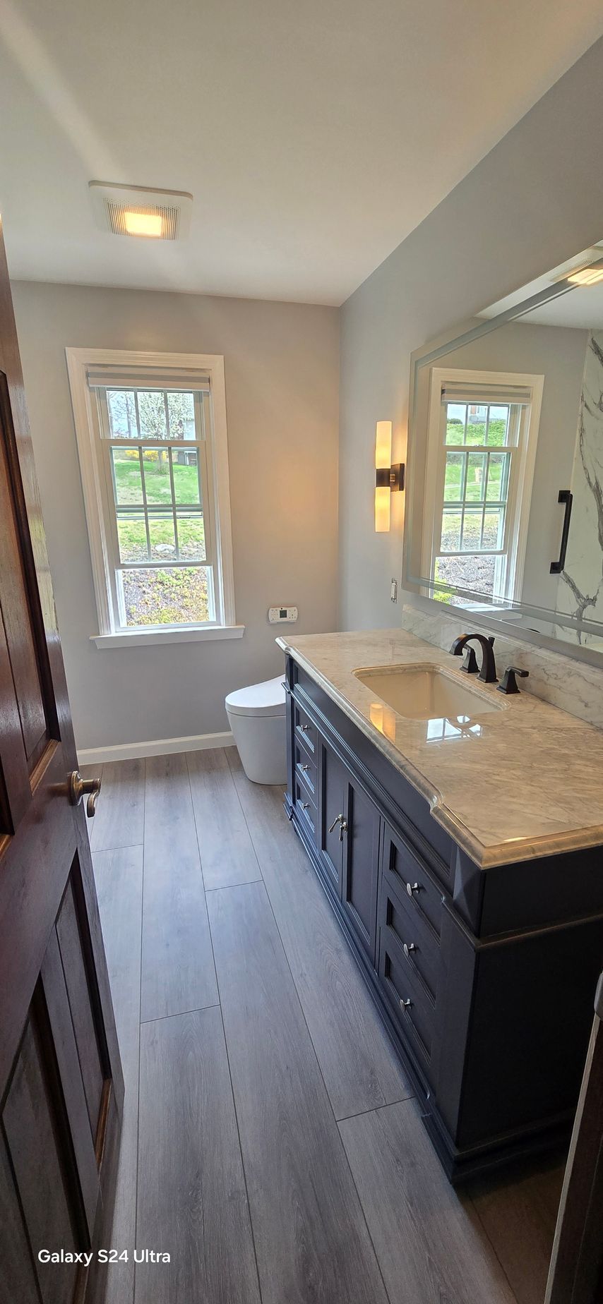 Bathroom with gray walls, dark wood vanity, and a window.