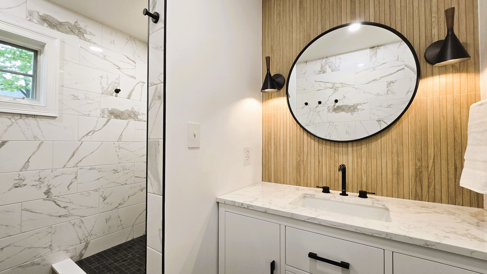 A bathroom with a sink , mirror and shower.