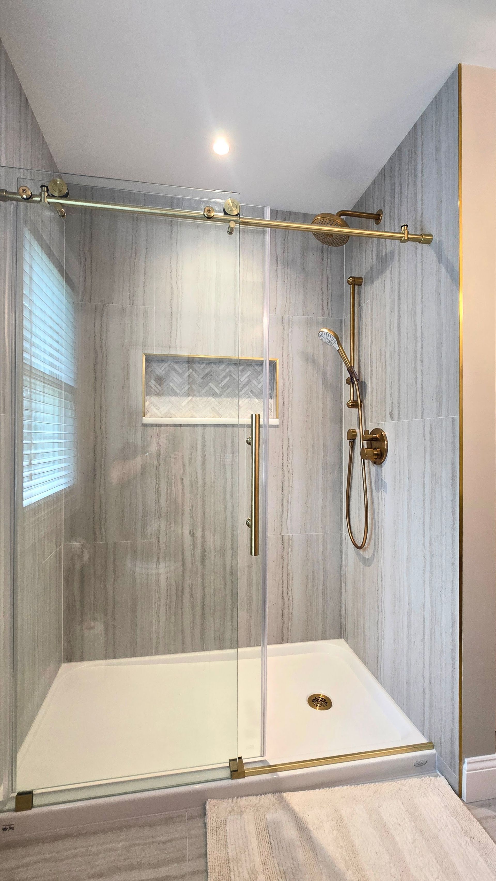 A shower with a sliding glass door and a shower head.