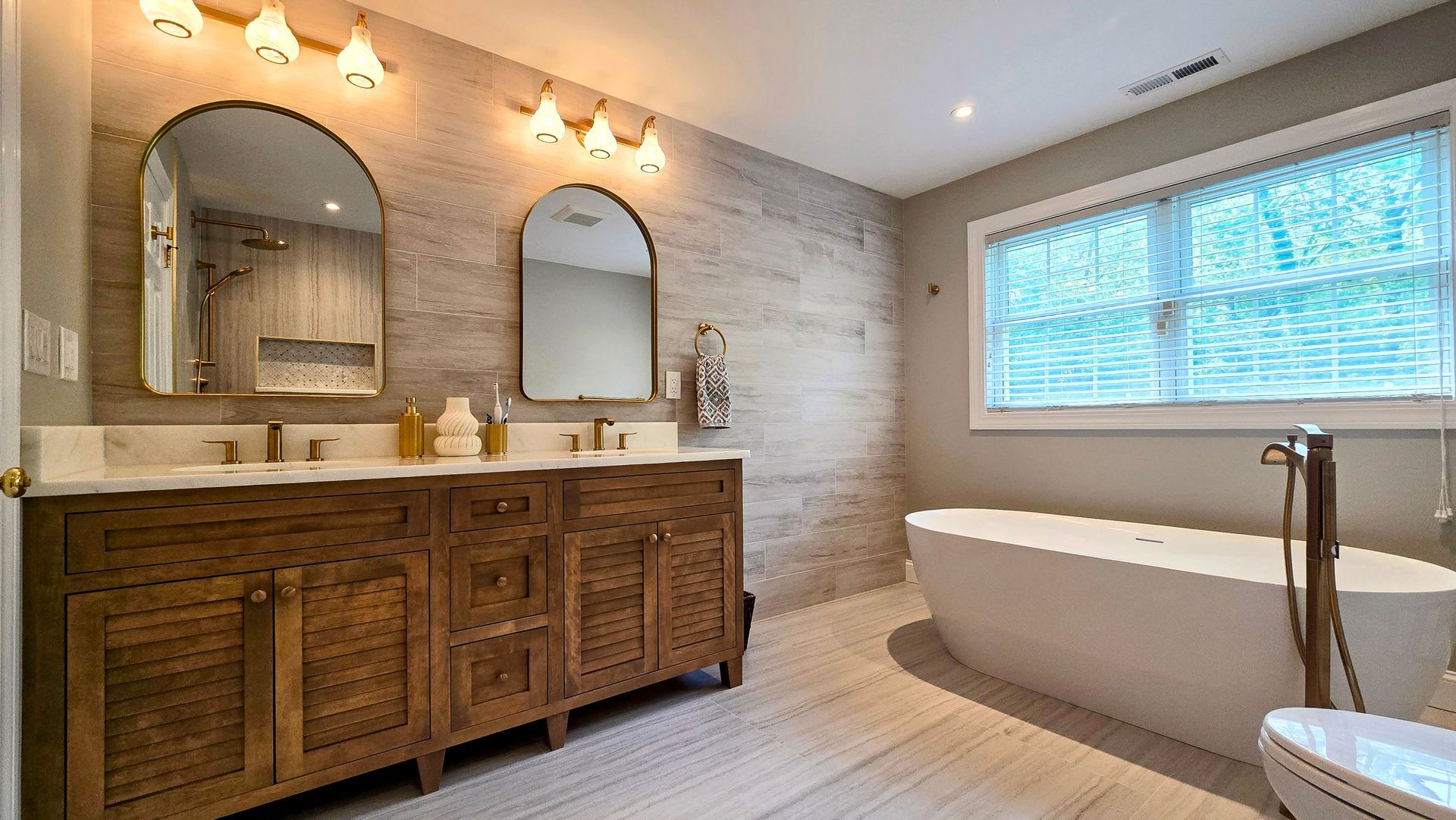 Bathroom in Prospect, CT with wooden vanity, oval tub, arched mirrors, and textured wall.