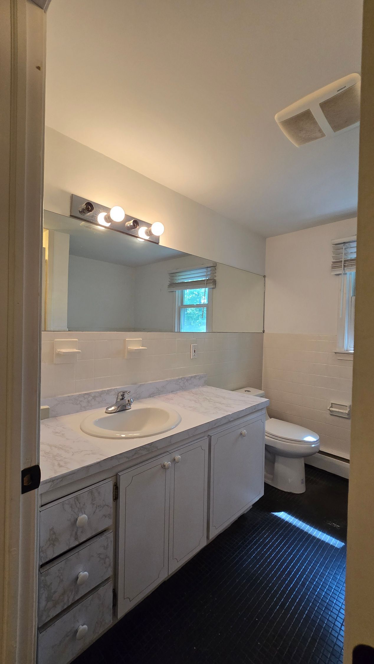 A bathroom with a sink , toilet and mirror.