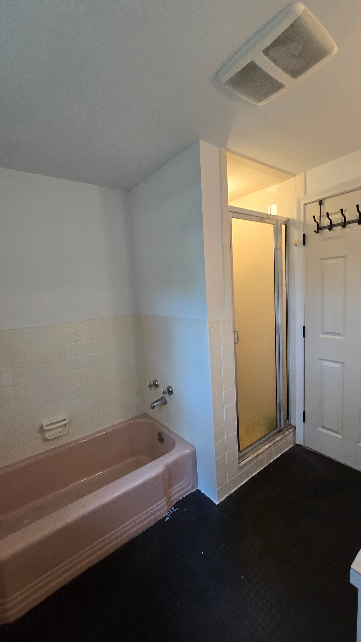 A bathroom with a pink tub and a walk in shower.