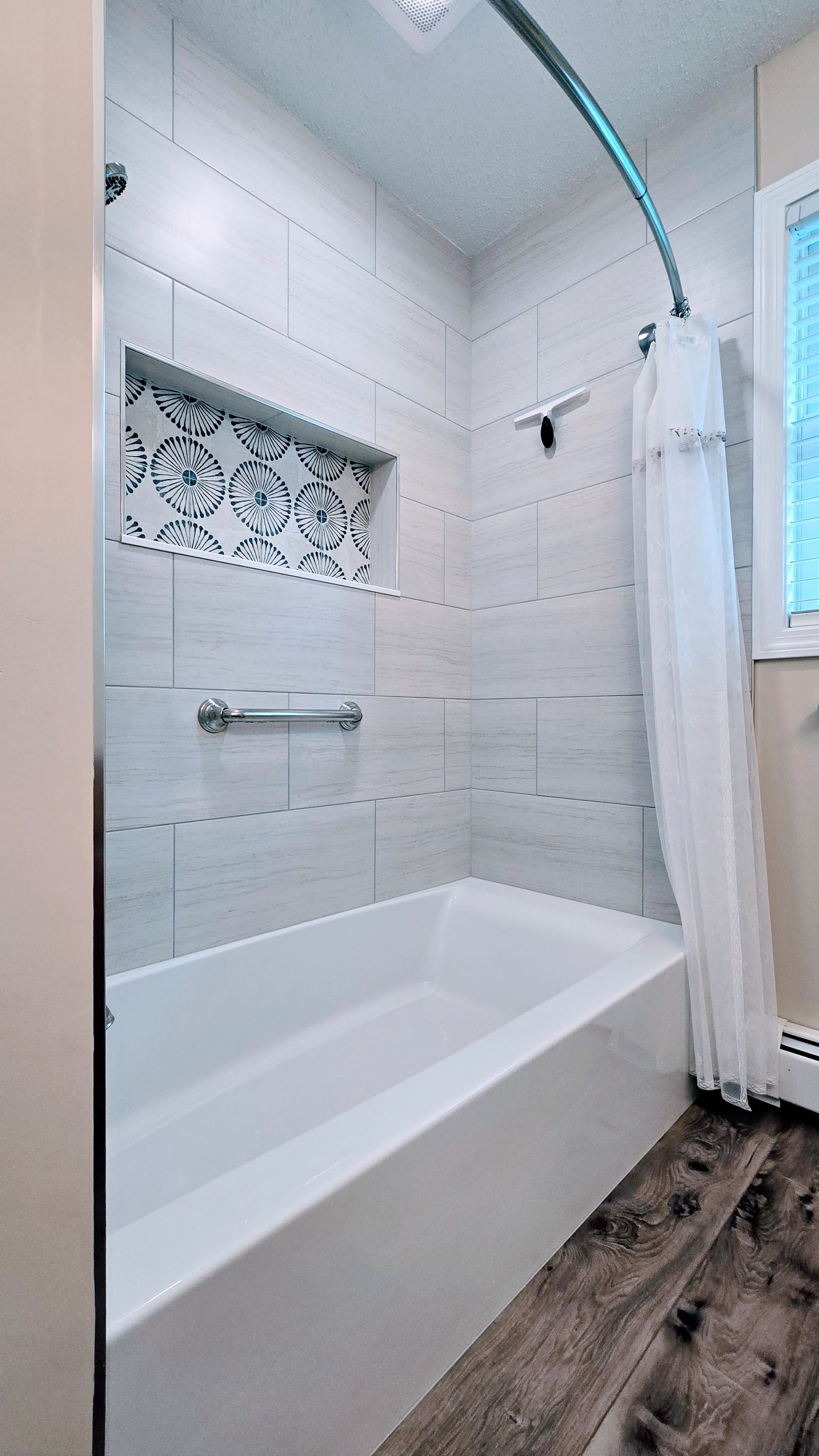 Modern bathroom with a white tub, tiled walls, and a patterned alcove.