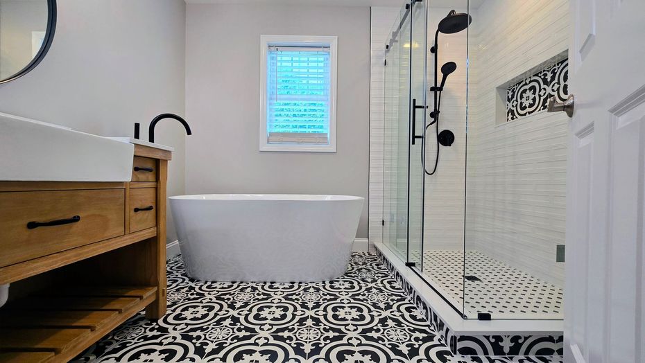 Modern Bathroom remodel in Prospect, CT with black and white patterned tile, a white tub, shower, and light wood vanity.