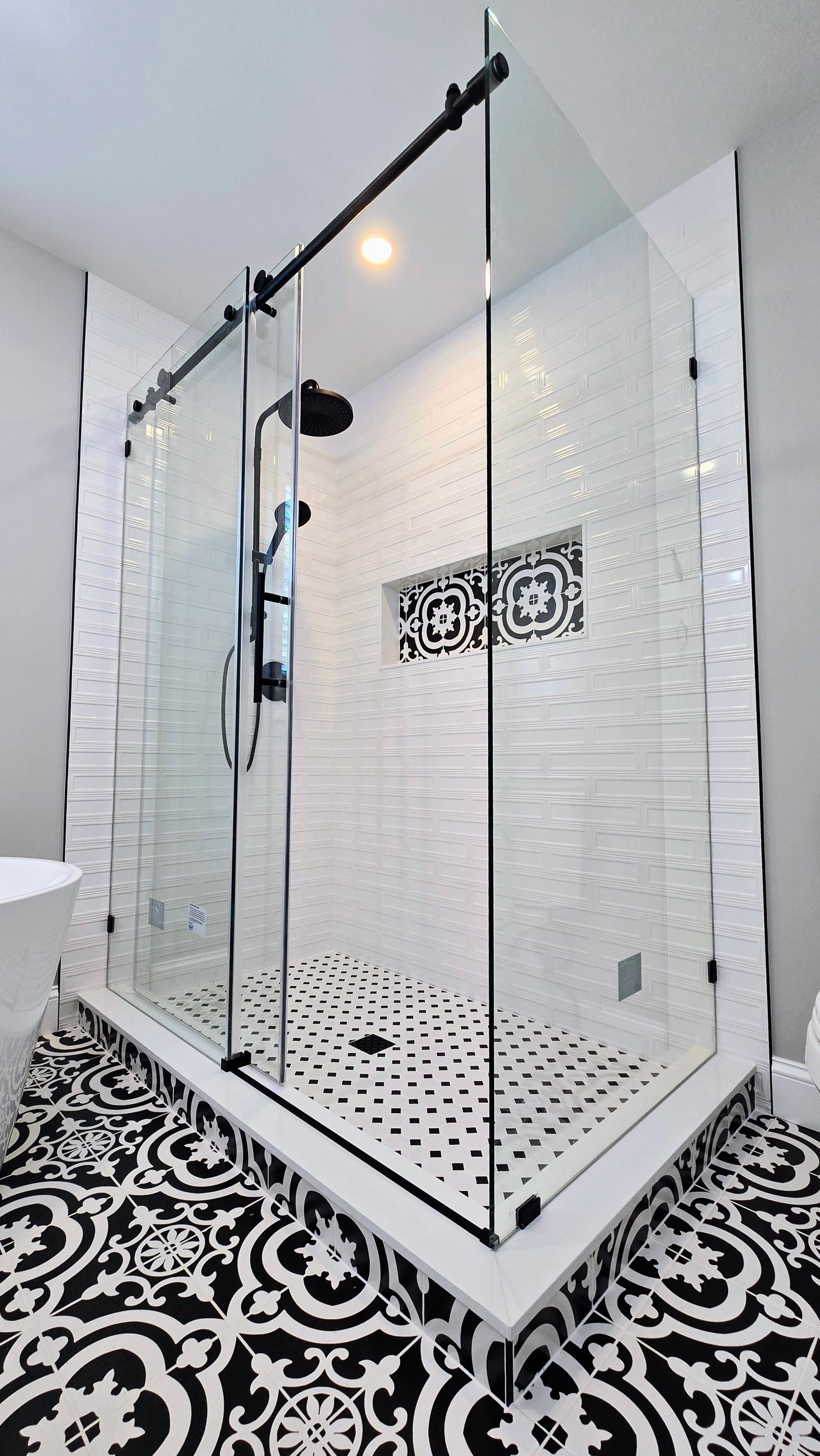 A Southington bathroom with a walk in shower with sliding glass doors and a black and white tile floor.