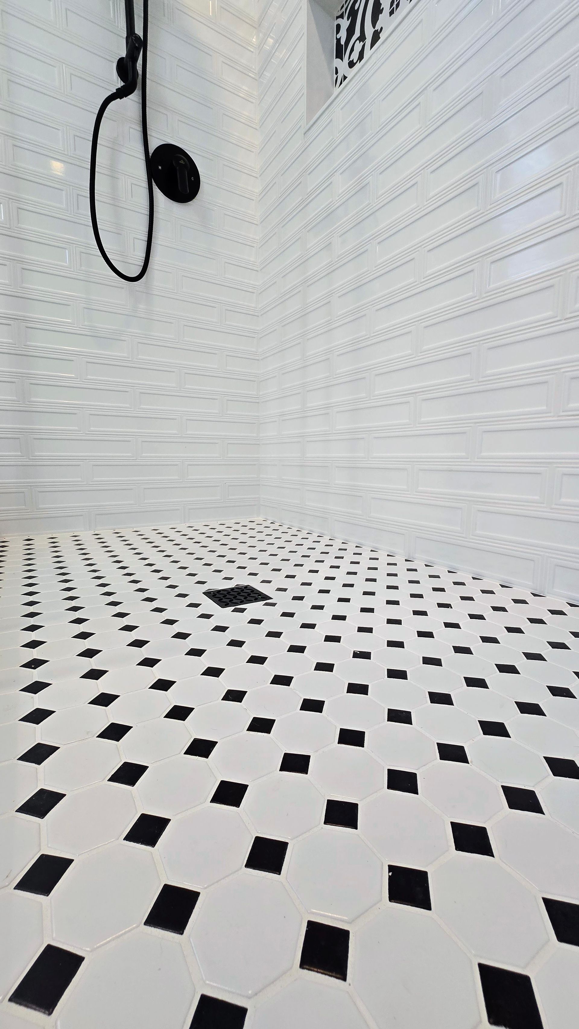 A Southington walk-in shower with black and white mosaic tiles on the shower floor
