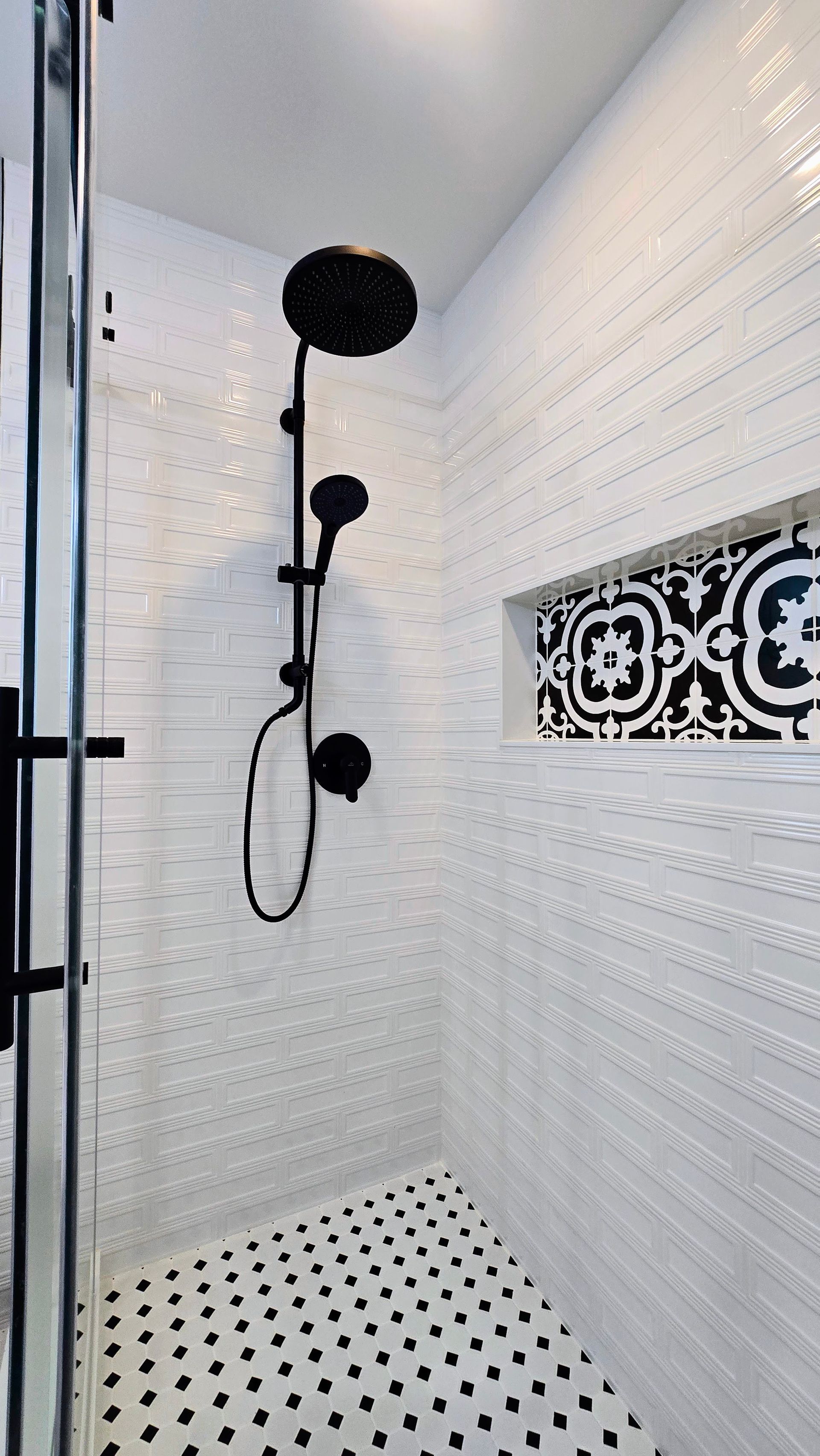 Bathroom with wood vanity, black fixtures, patterned floor, and white tub.