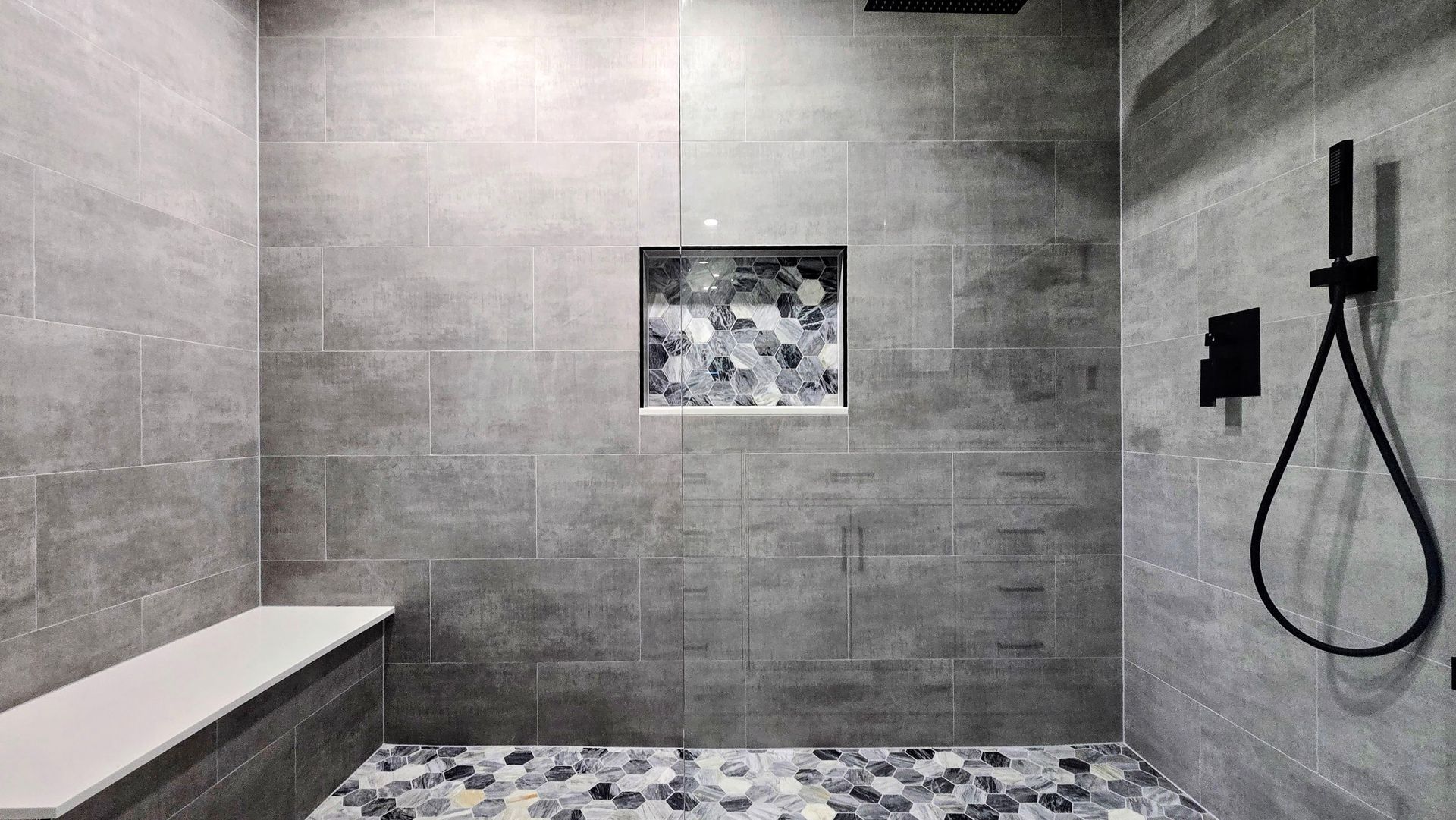A walk in shower with a bench and a shower head.