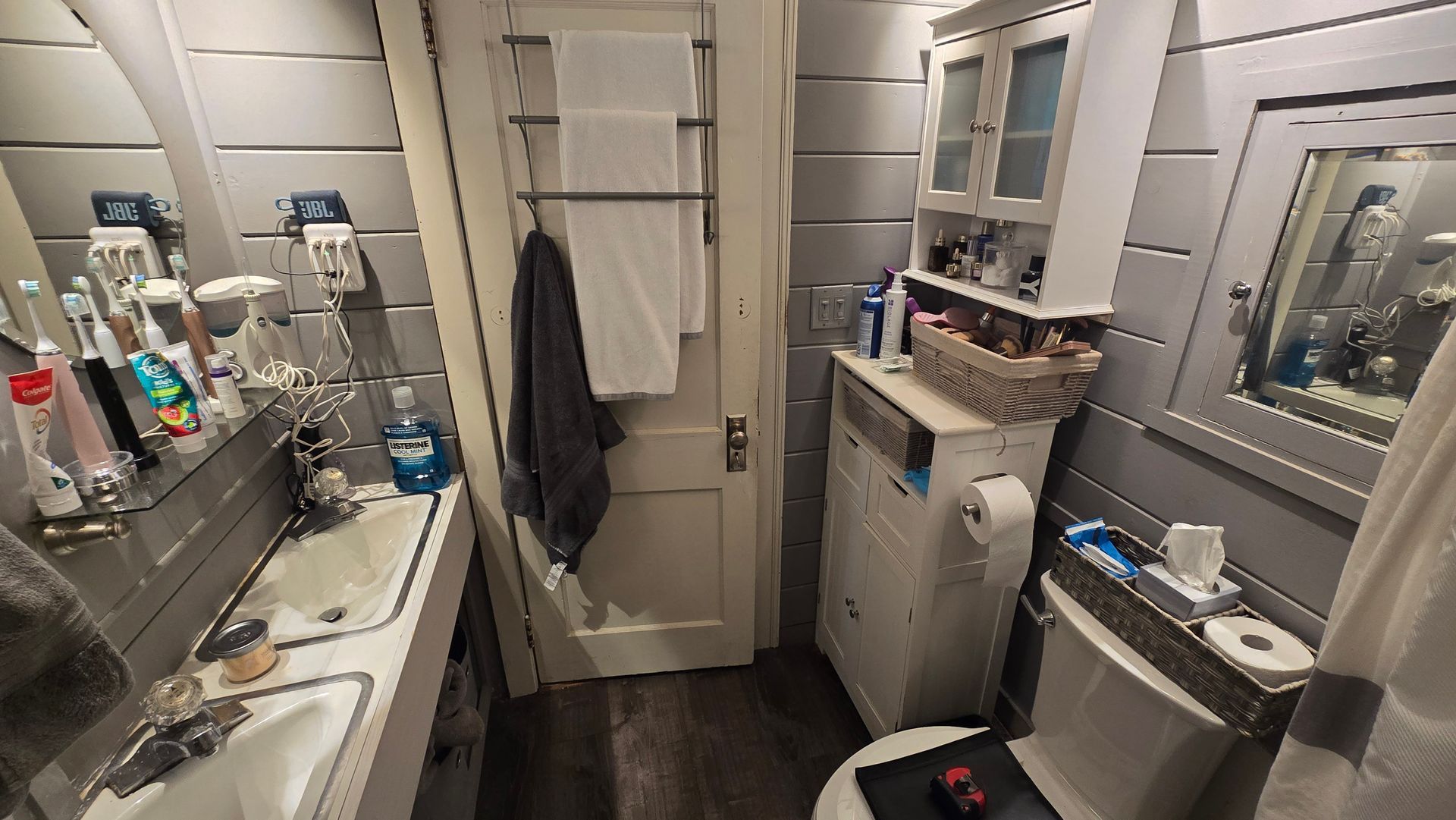 Small West Hartford bathroom with a sink, toilet, washing machine, and cabinet. Gray and white color scheme.