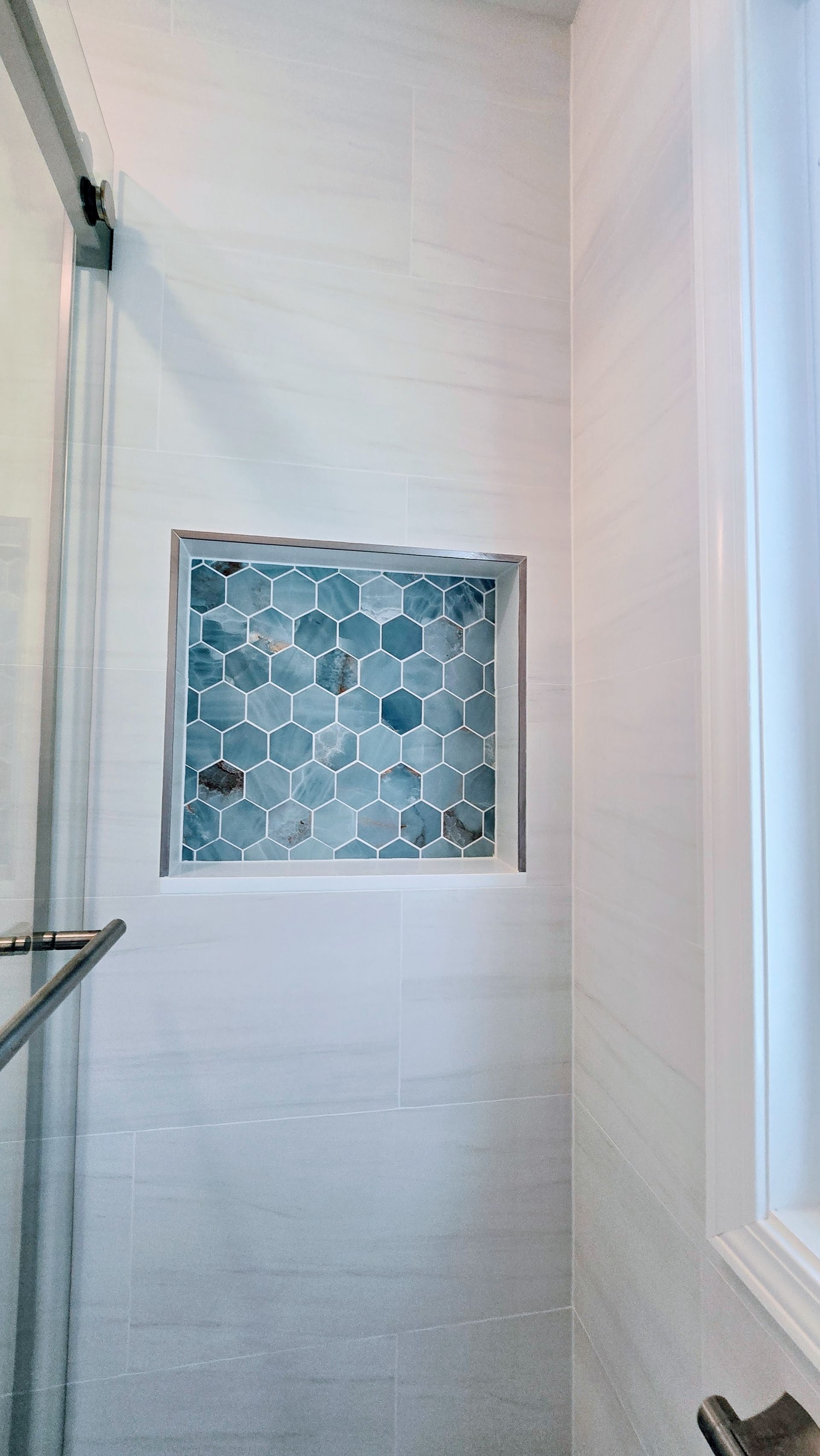 A shower with a built in shelf and a shower head