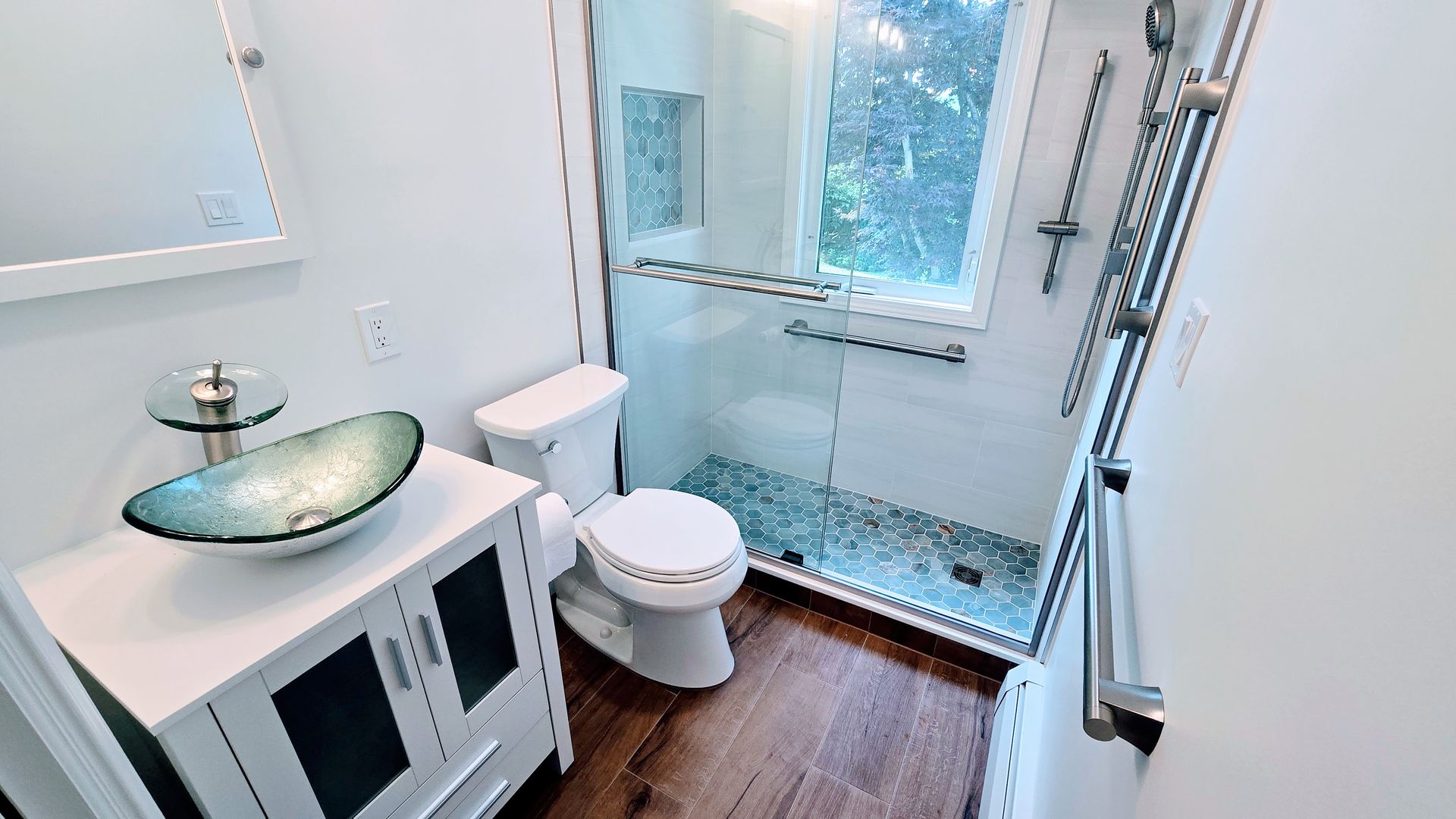 Small, modern bathroom with white walls, a glass shower, and a blue glass sink.